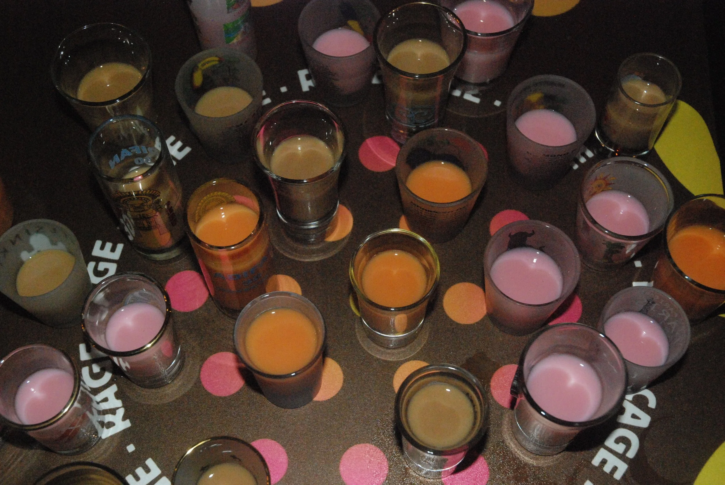 Mesa con variedad de shots de 7 Pecados en tonos rosados y dorados, incluyendo la fresa lujuriosa, lúcuma golosa y pereza de café, es una crema de pisco peruana ideal para activaciones, eventos y fiestas privadas.