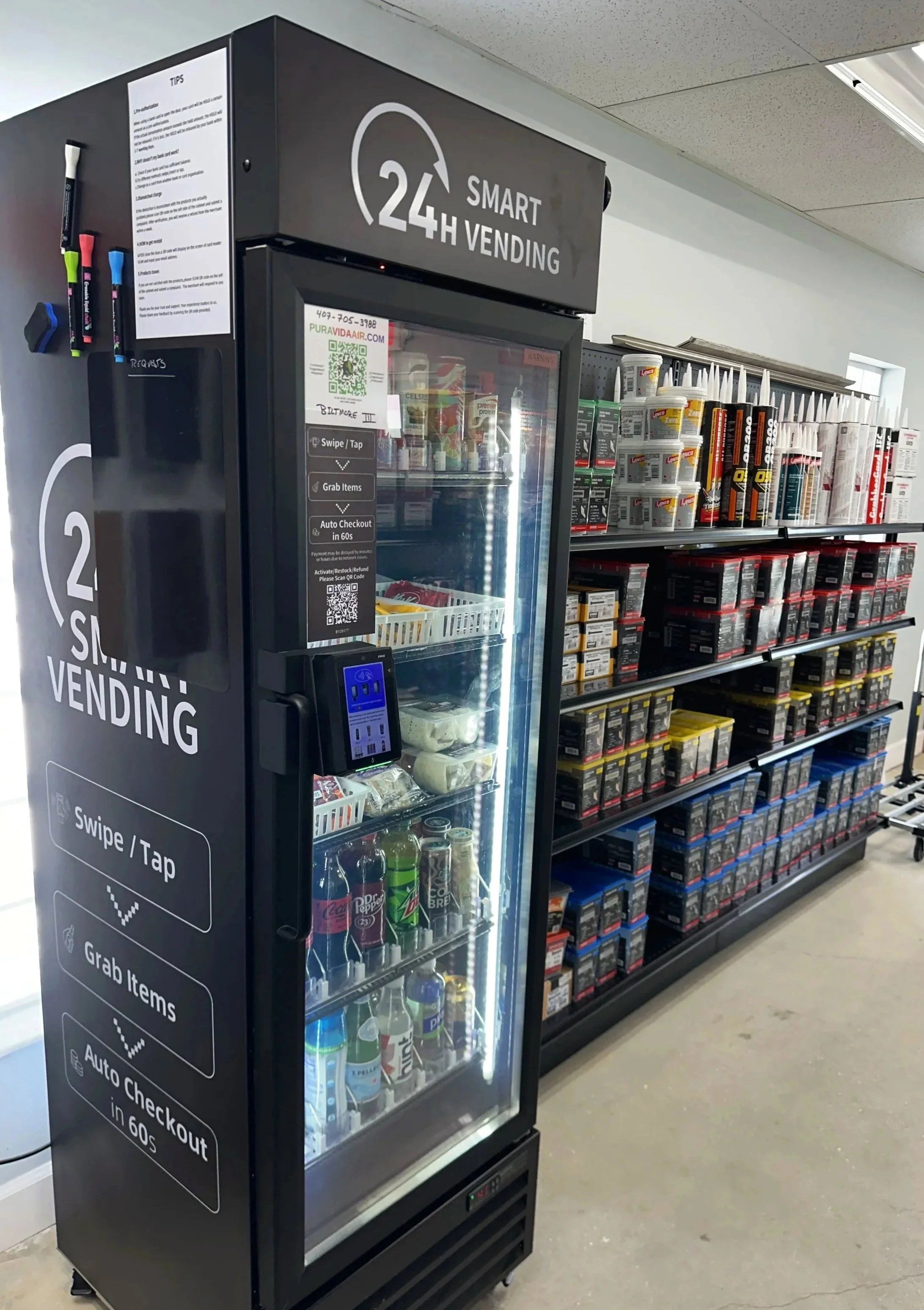 A 24-hour smart vending machine stocked with snacks and beverages, located in a store aisle with shelves of products in the background.