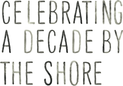 Text that reads 'Celebrating a Decade by the Shore' in black and gray letters on a white background.
