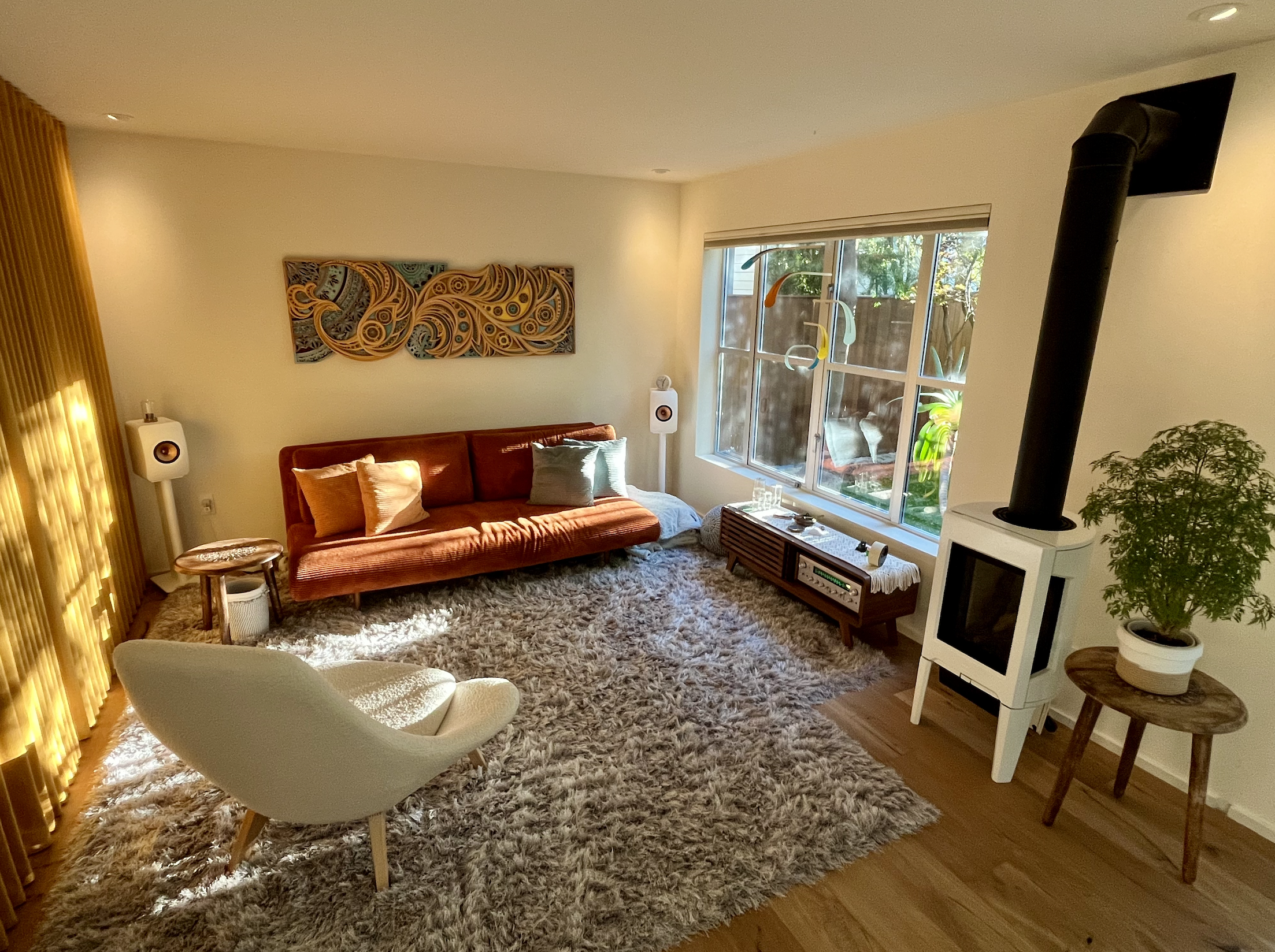 Warm, sunlit session room in San Francisco with sofa, armchair, and garden view.