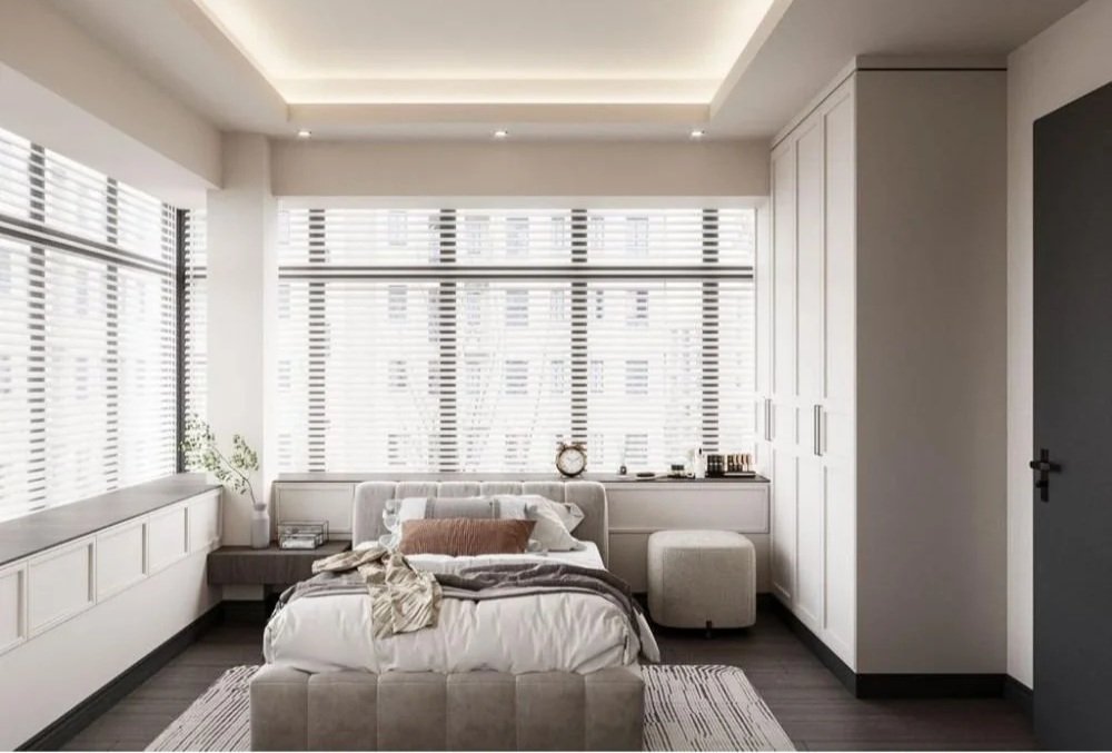 Modern bedroom with large windows, white walls, built-in storage, and a bed with pillows and a blanket.