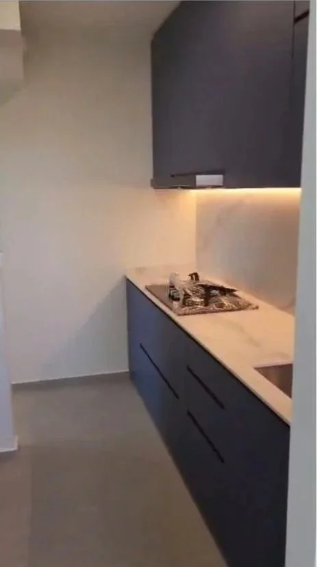 Modern kitchen with dark blue cabinets, white countertop, gas stove, and under-cabinet lighting.