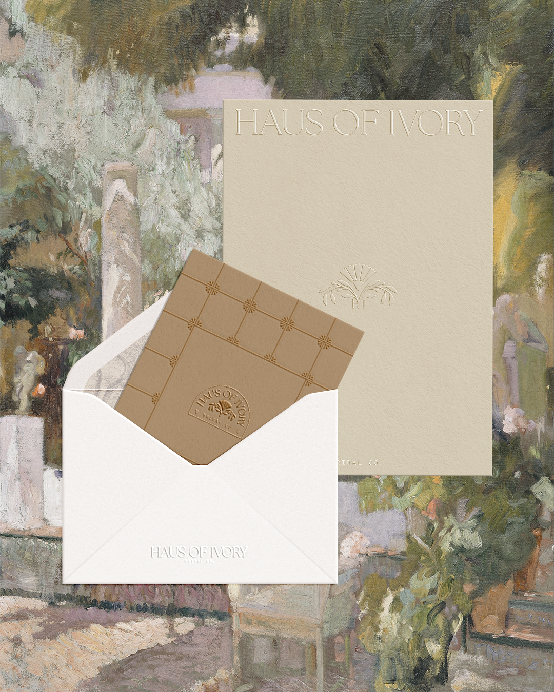 A box of Haus of Ivory chocolates in a white envelope and a cream-colored box, set against a background of a garden scene with lush greenery and a stone pathway.