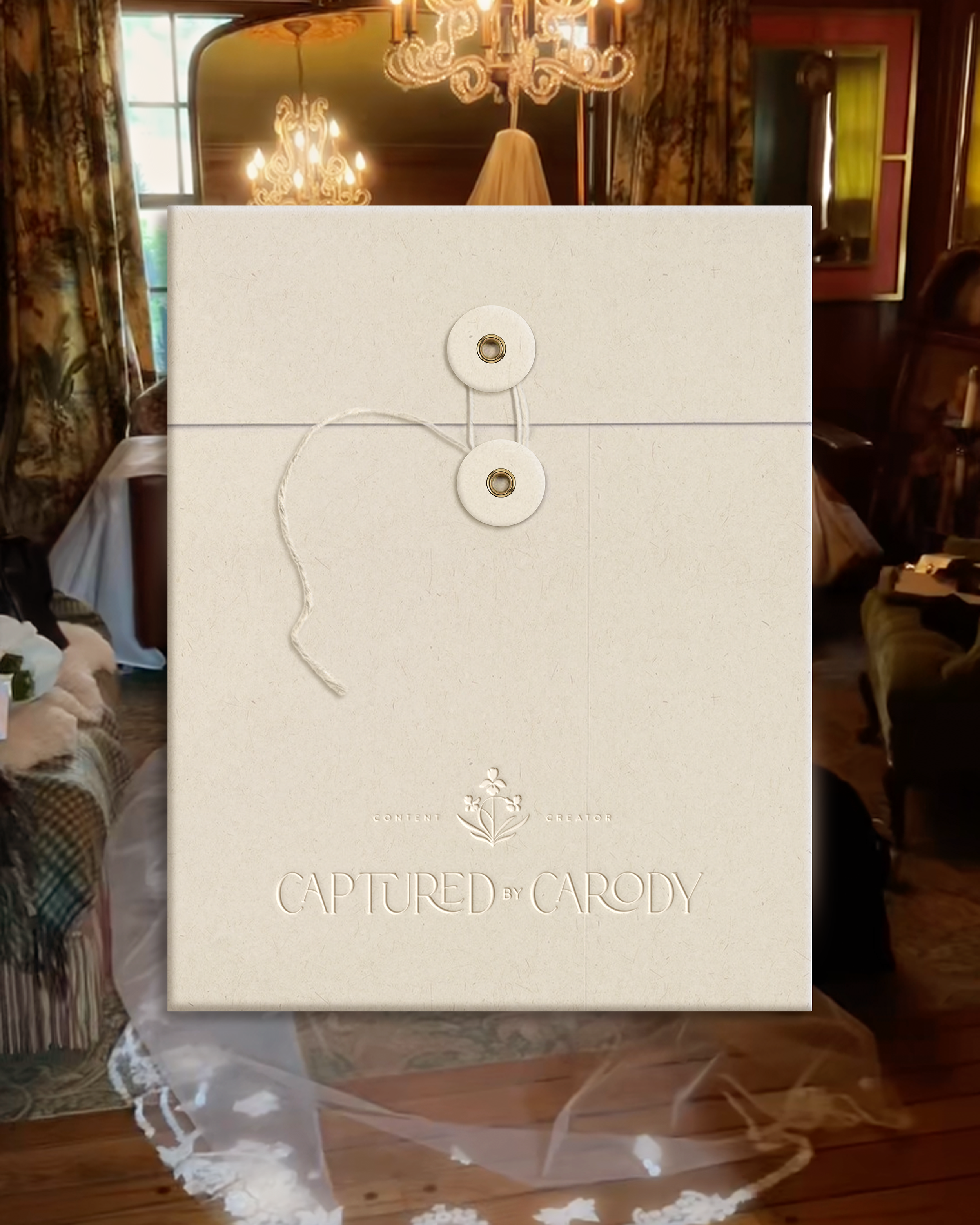 The image shows the back of a framed artwork or photograph with string and metal hooks, set against a vintage, ornately decorated room with chandeliers, floral curtains, and antique furniture.