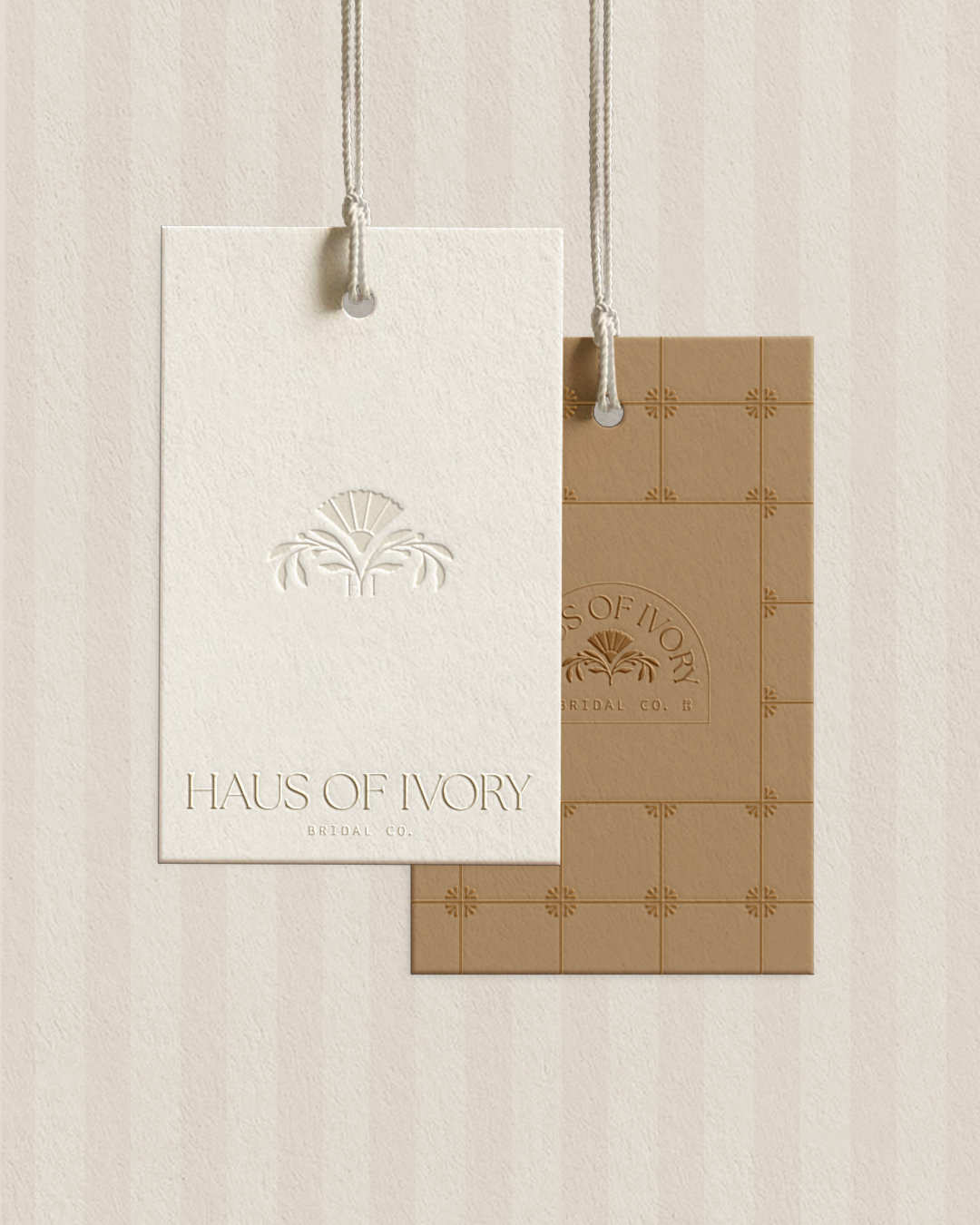 Two tags with the words "Haus of Ivory Bridal Co."; one white and one tan, hanging on a wall.