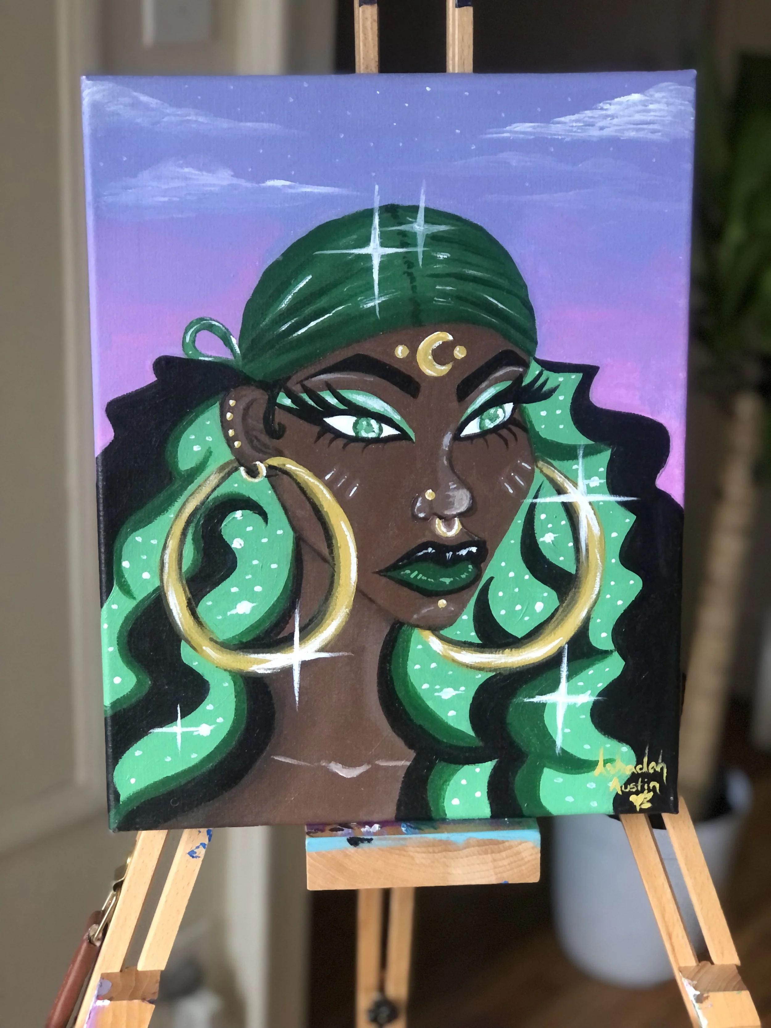 A vibrant painting of a woman with dark skin, green hair, and gold jewelry, featuring large hoop earrings, a moon forehead decoration, and sparkling accents on her hair and face, set against a purple and blue background.