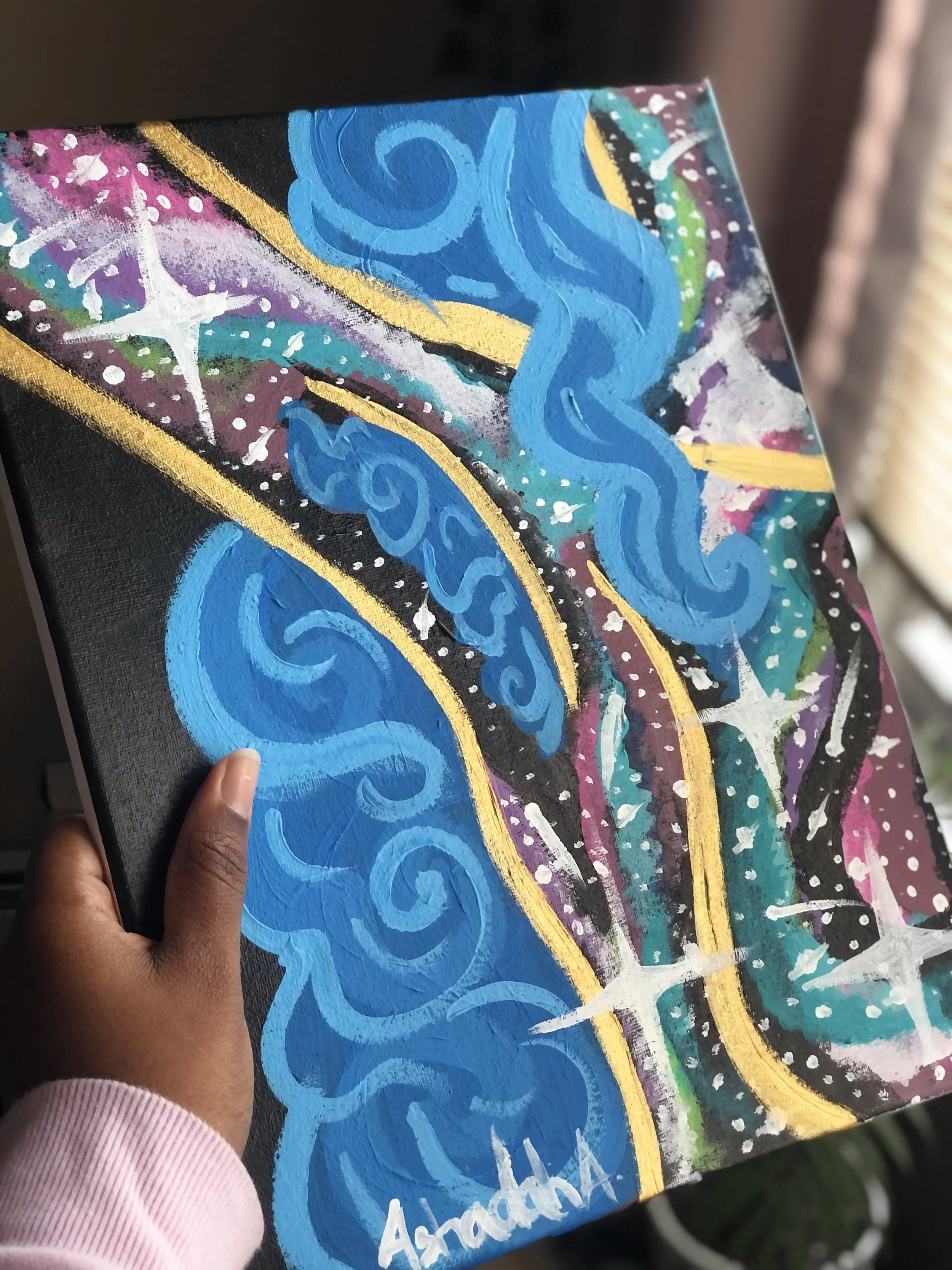 Close-up of an abstract painting featuring swirling blue shapes, sprinkled white dots, and a background of purple, black, and green colors with gold lines and white star-like accents.