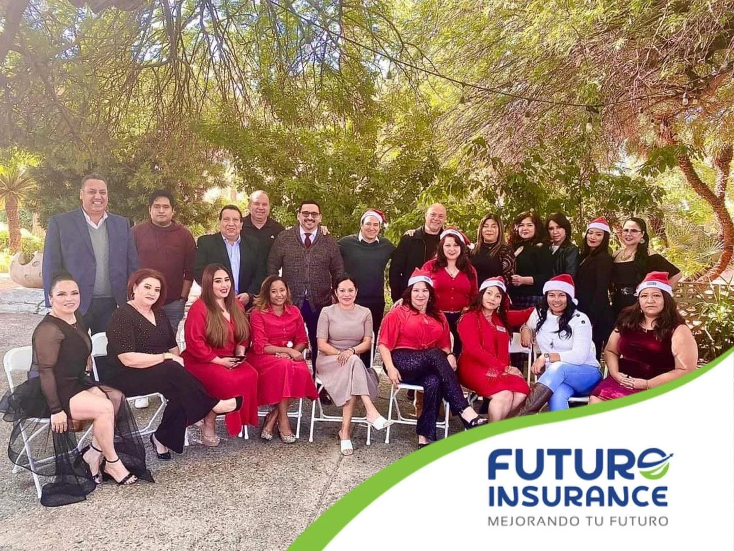 Grupo de personas en un evento navideño, algunos con gorros de Santa, en un área exterior con árboles y vegetación, logotipo de Future Insurance y el lema 'Mejorando tu futuro' en la esquina inferior derecha.