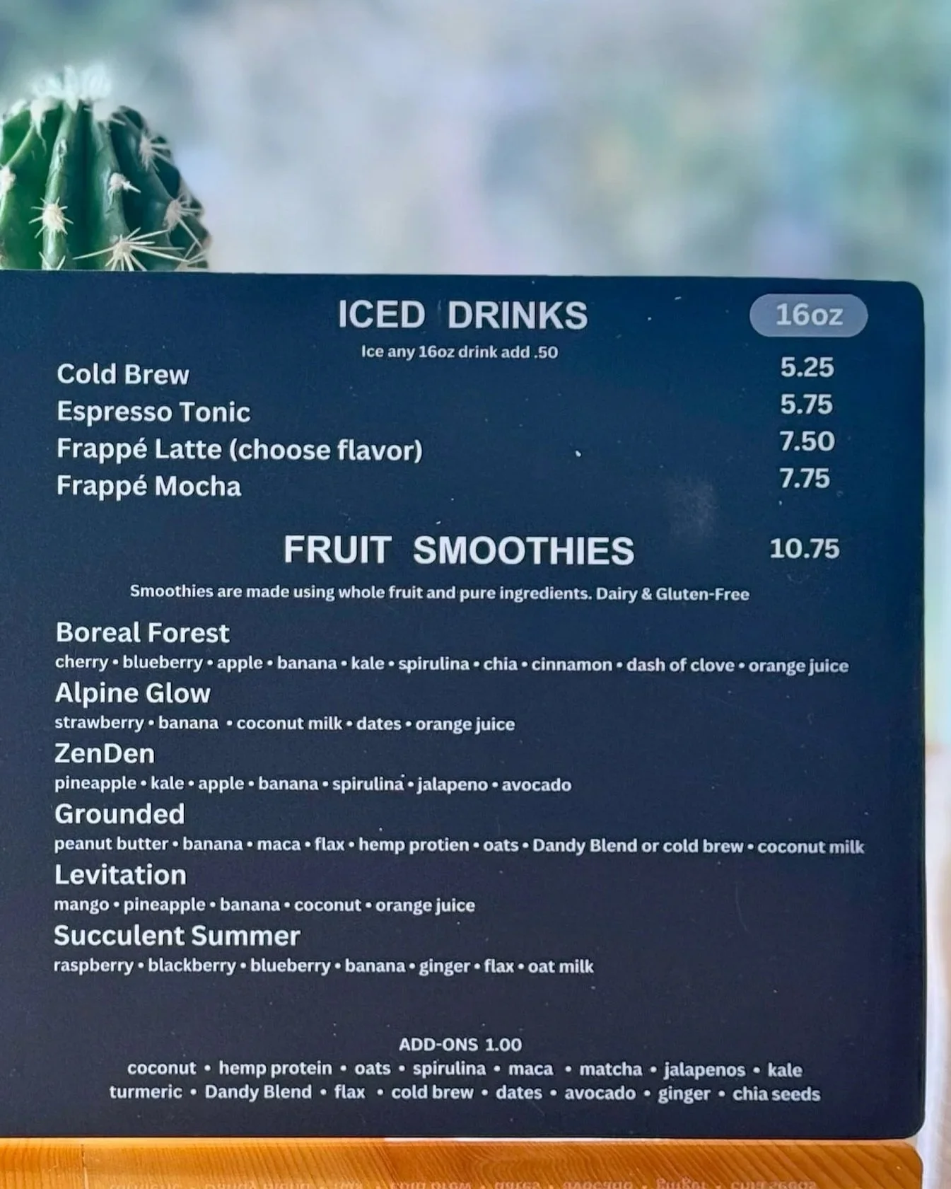 Menu listing iced drinks, including cold brew, espresso tonic, frappé latte (flavor choices), and frappé mocha, with prices ranging from $5.25 to $7.75. Also features fruit smoothies with options such as Boreal Forest, Alpine Glow, ZenDen, Grounded, 