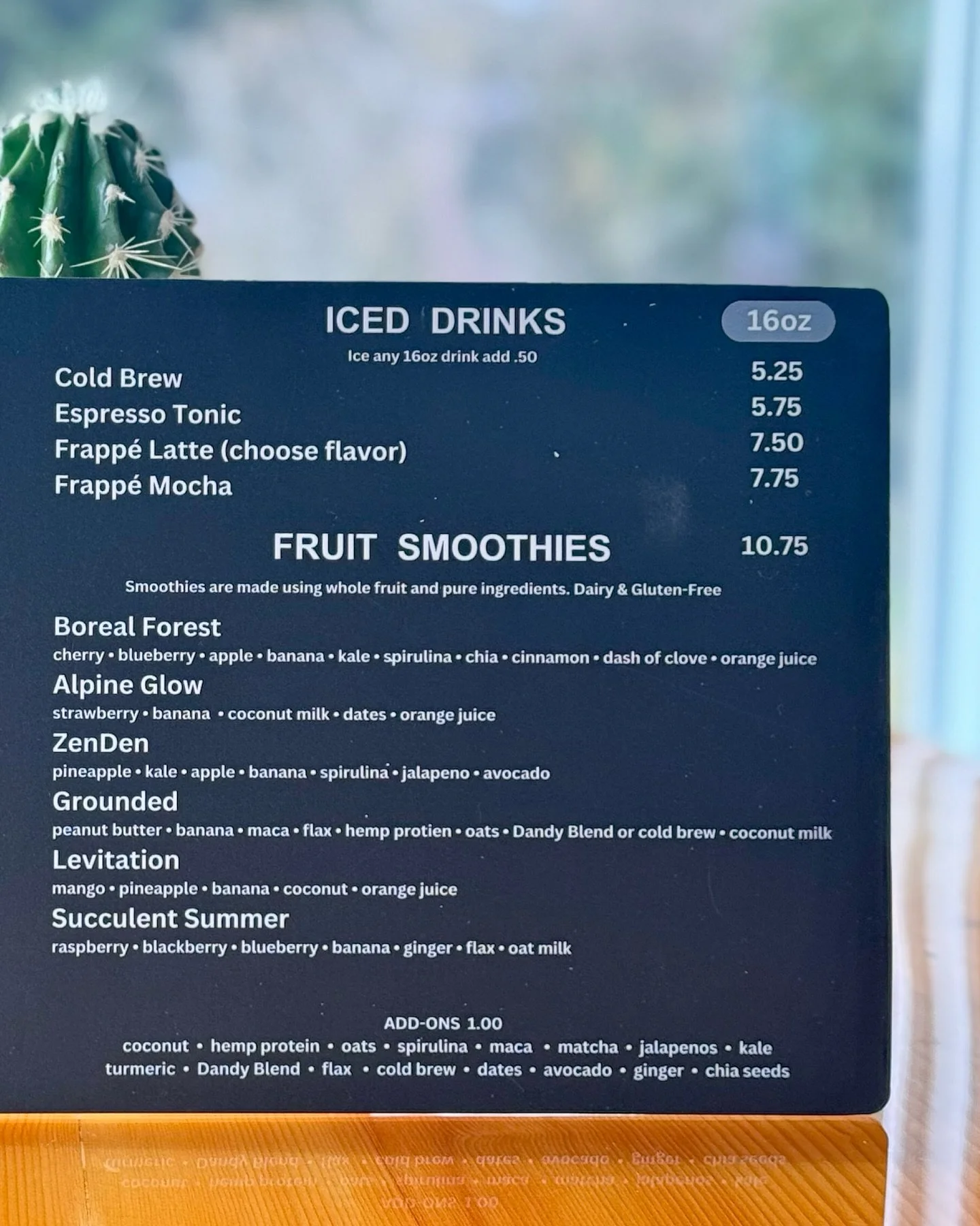 Menu listing iced drinks, including cold brew, espresso tonic, frappé latte (flavor choices), and frappé mocha, with prices ranging from $5.25 to $7.75. Also features fruit smoothies with options such as Boreal Forest, Alpine Glow, ZenDen, Grounded,