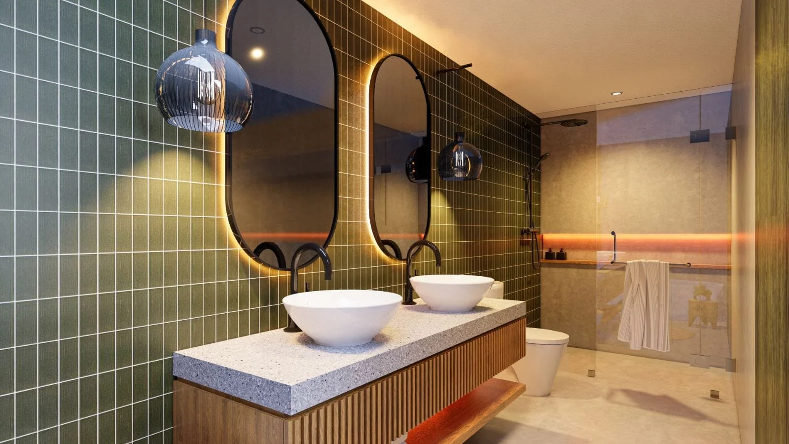 Modern bathroom with green tiled wall, two oval mirrors with backlit LED lighting, two vessel sinks with black faucets on a speckled countertop, black pendant light fixtures, and a walk-in shower area with a glass partition and beige wall tiles, feat