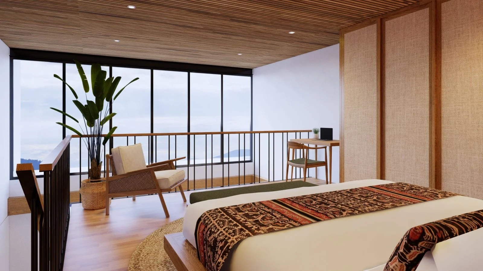 A modern hotel room with a large bed, patterned bedding, a sitting area with a chair and a tall plant, a small desk with a computer, and large windows showing a view of clouds and distant mountains.