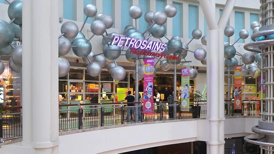 Interior of the Petrosains interactive science museum with metallic sphere decorations and visitors exploring exhibits.