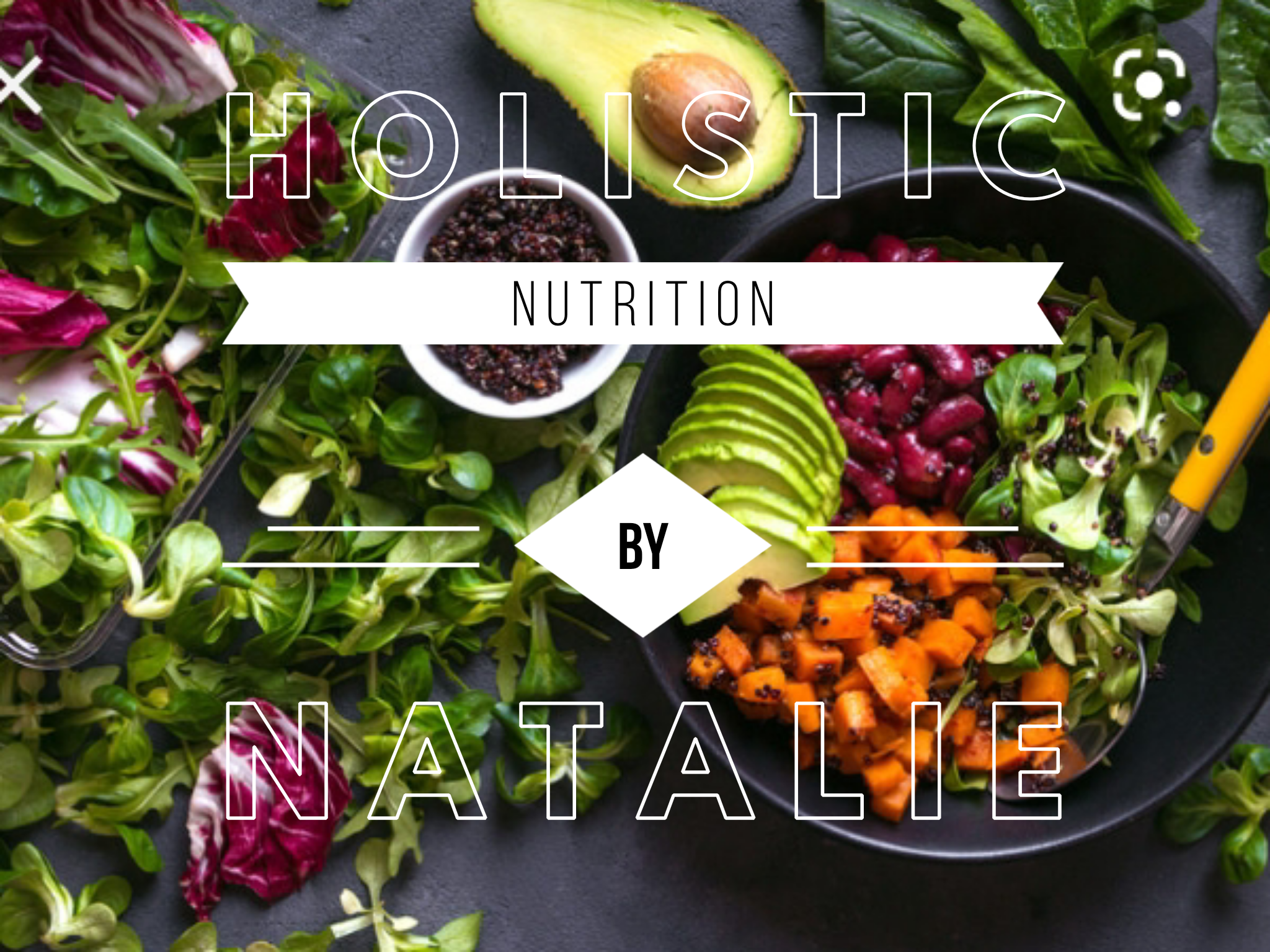 An assortment of fresh vegetables and greens, including avocado, avocado slices, red beans, chopped carrots, and various leafy greens on a dark surface with a yellow-handled utensil.