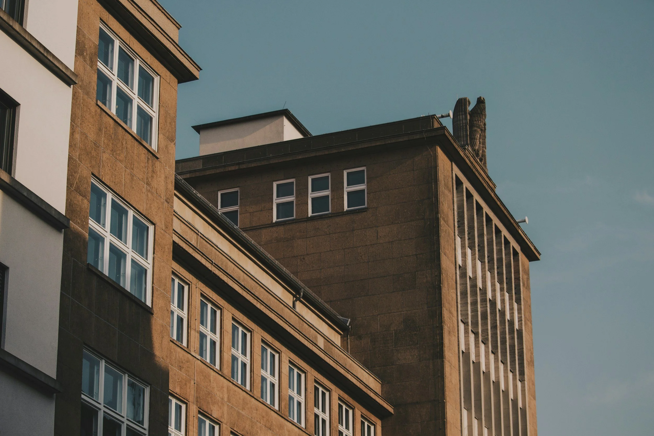 Close-up of urban building facades with multiple windows against a blue sky.
