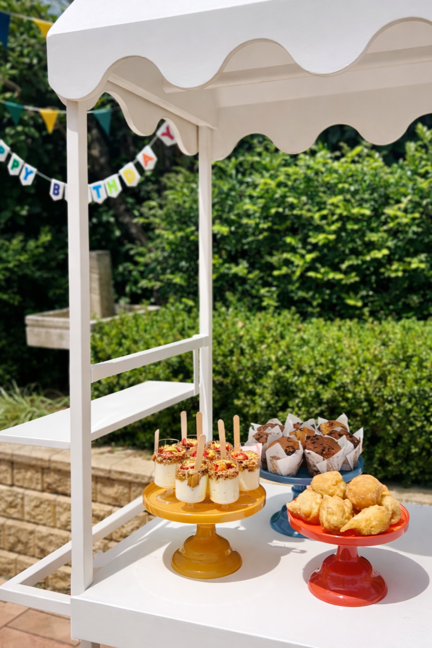 Birthday catering dessert table by 10 Pounds (Pyrmont)  with pastries and sweets, set up alongside a coffee cart at an outdoor event.