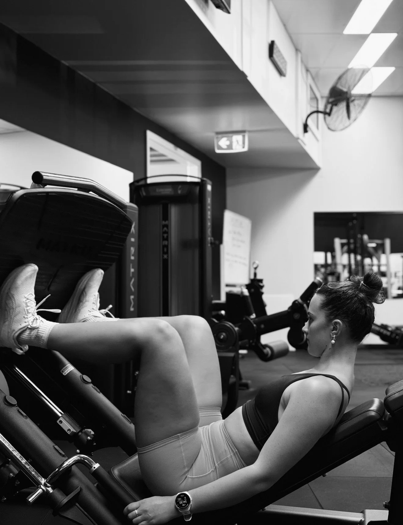 A woman in athletic attire doing leg exercises on a leg press machine in a gym.