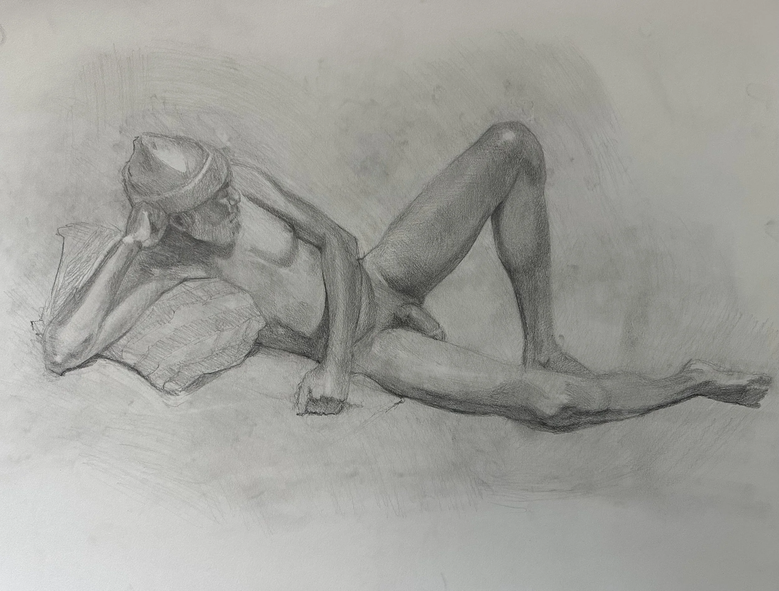 Pencil drawing of a man lying on his side, leaning against a pillow. He wears a beanie, with his left arm bent and his hand supporting his head. He is nude, with one leg bent and the other extended out