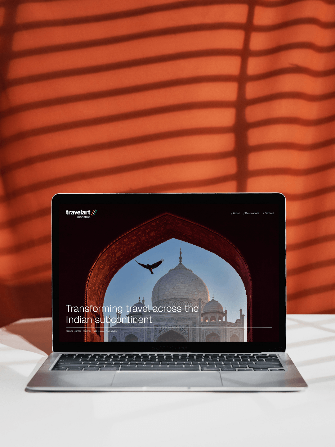 Laptop displaying travel website with an image of the Taj Mahal, framed by an ornate archway.