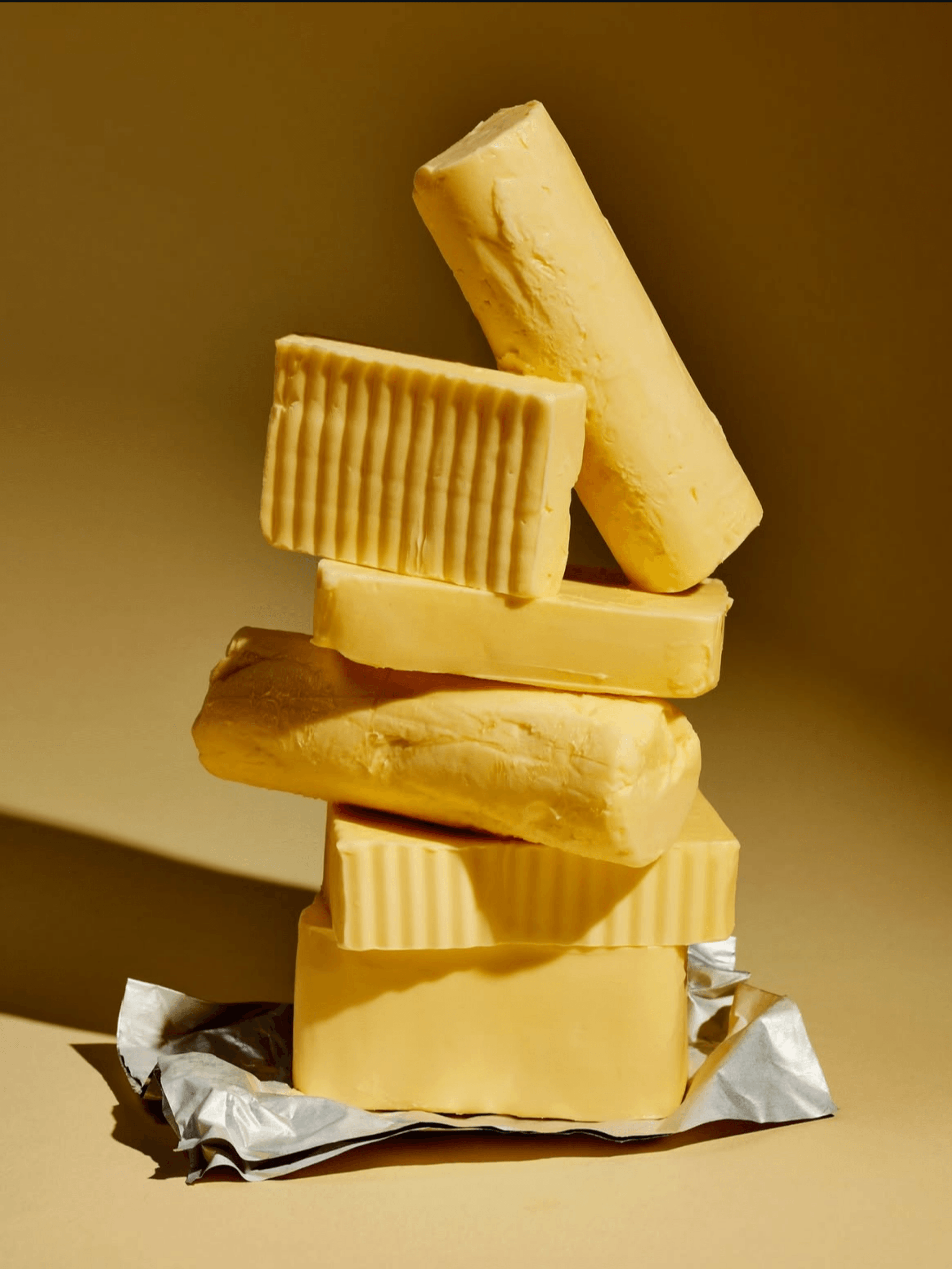Pile of assorted cheeses stacked on top of each other, some wrapped in foil.