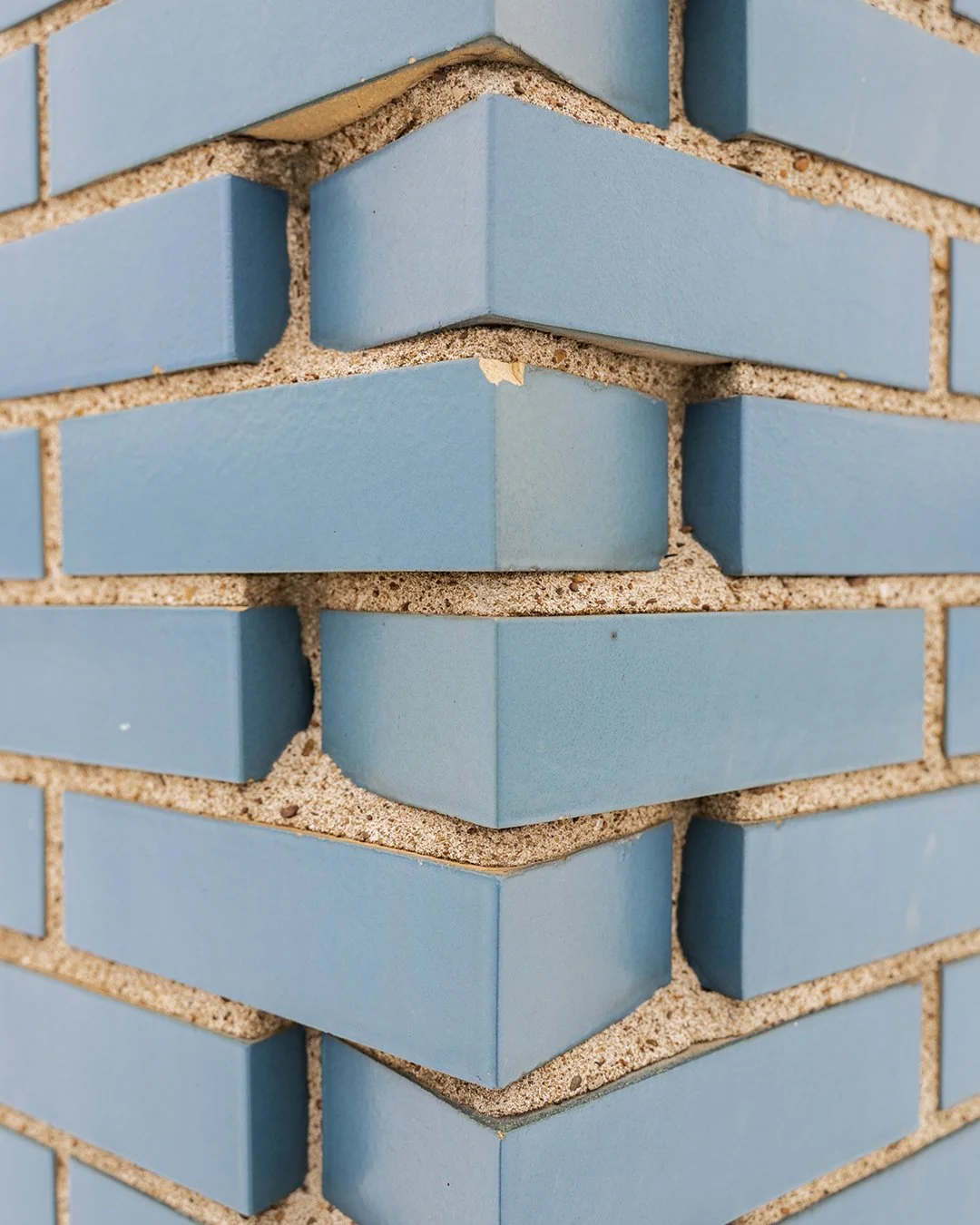 Close-up of a blue brick wall with beige mortar.