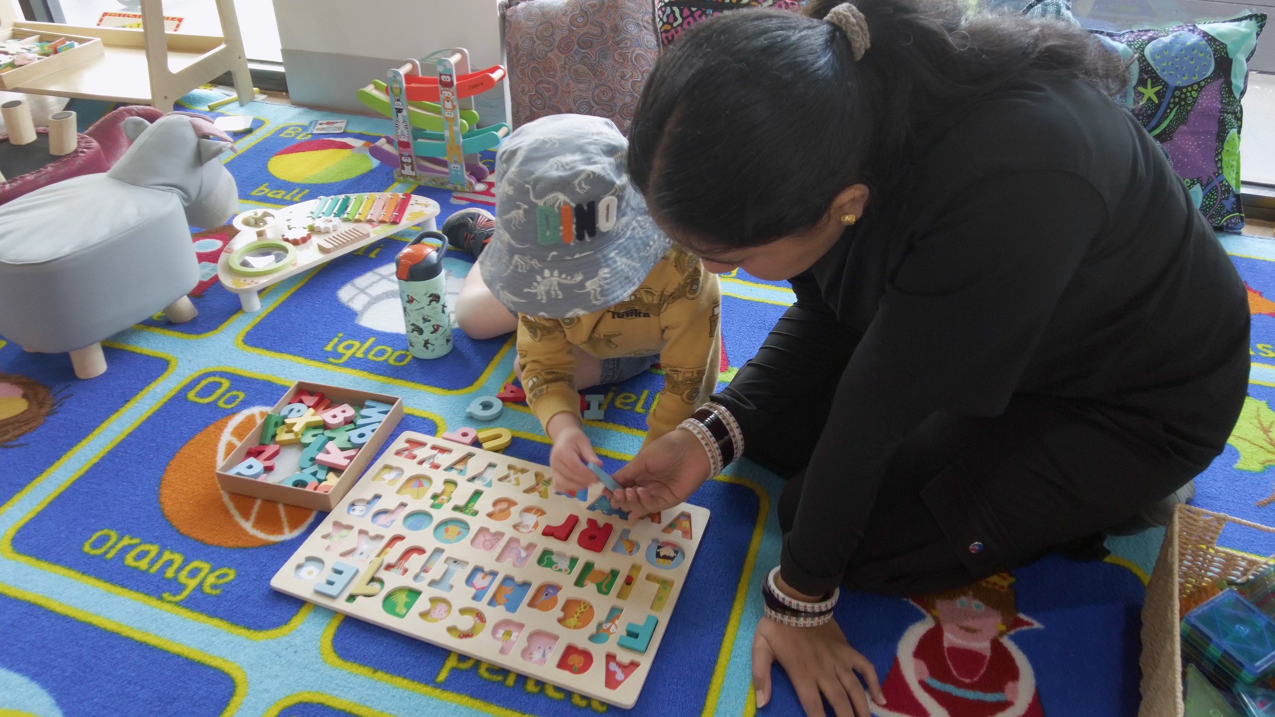 A young girl playing with colorful paper cutouts on a table.