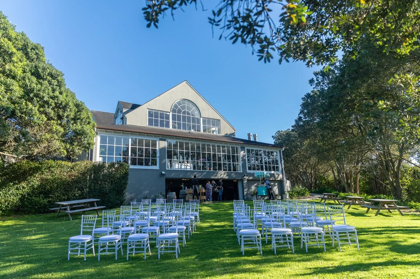 At Ōrākei Bay, floor-to-ceiling glass windows flood every space with natural light, framing views of the trees and the sparkling basin beyond. From the moment guests arrive to the final toast, the setting feels open, bright, and effortlessly beautifu