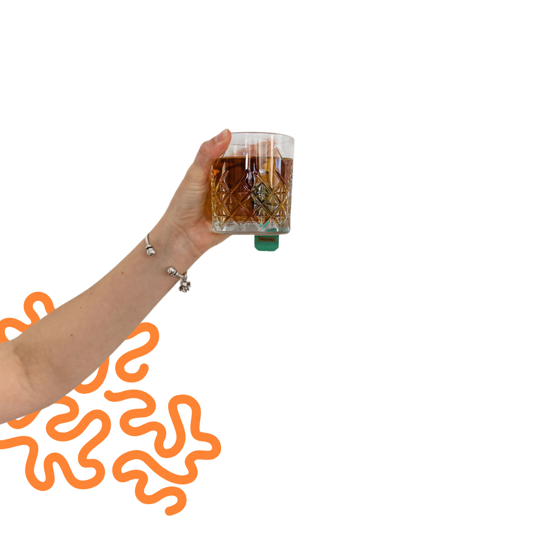 A person's hand holding a glass of dark soda with ice cubes against a black background.
