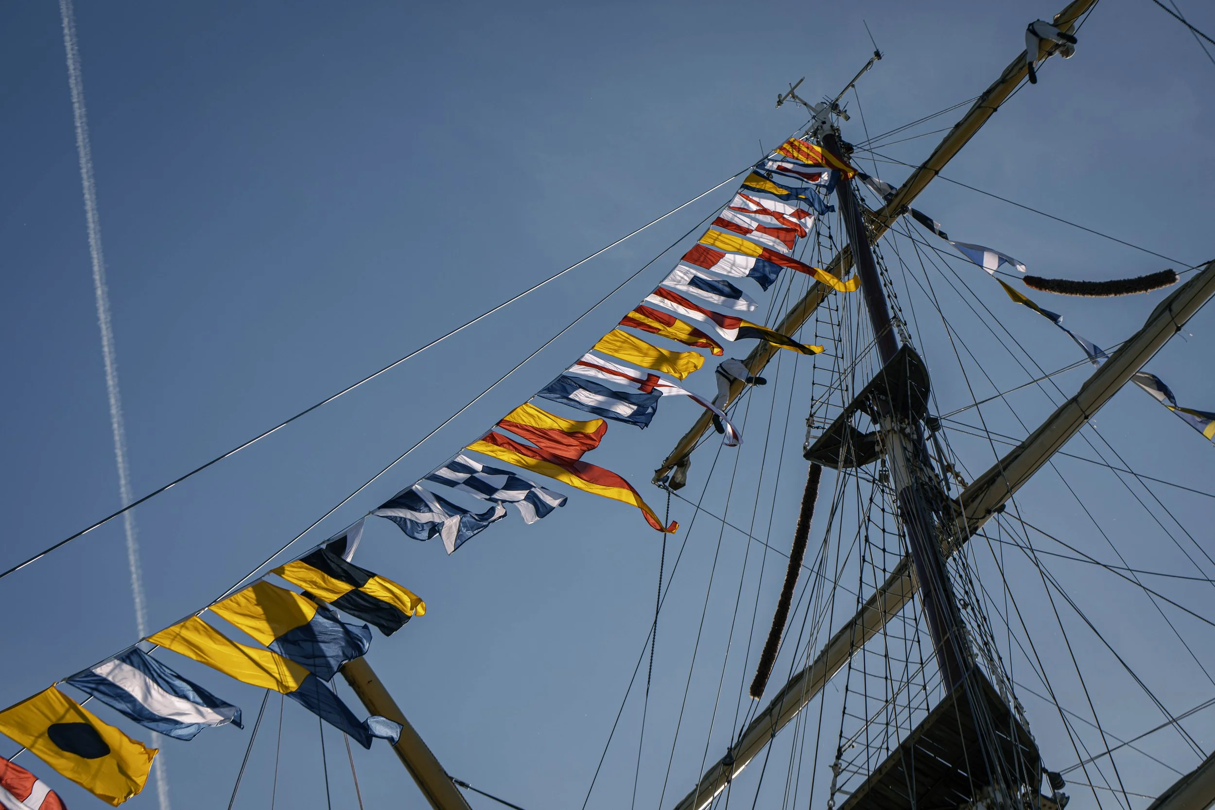 Aufnahme eines Schiffsmastes mit bunten Flaggen gegen blauen Himmel.