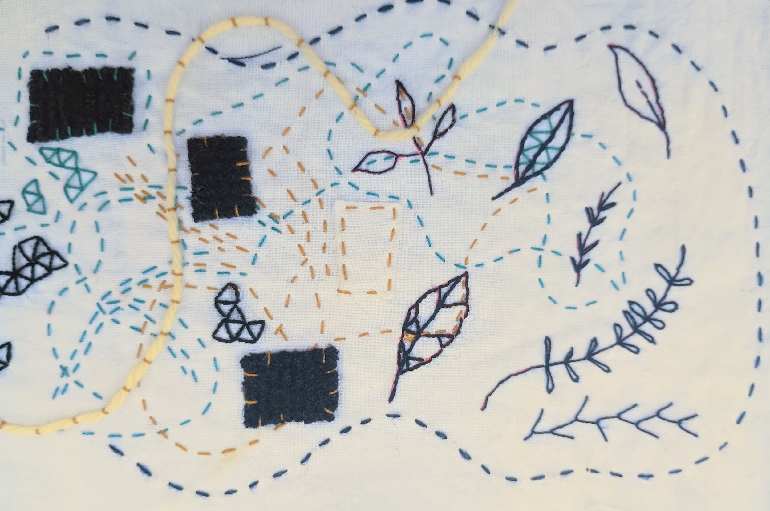 Embroidery of a branch with leaves on fabric, with colorful dashed lines and stitched shapes around it.