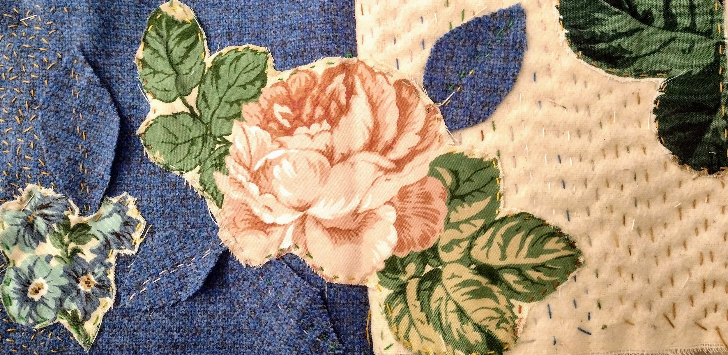 Close-up of fabric pieces with floral and leaf patterns, sewn together with visible stitching.