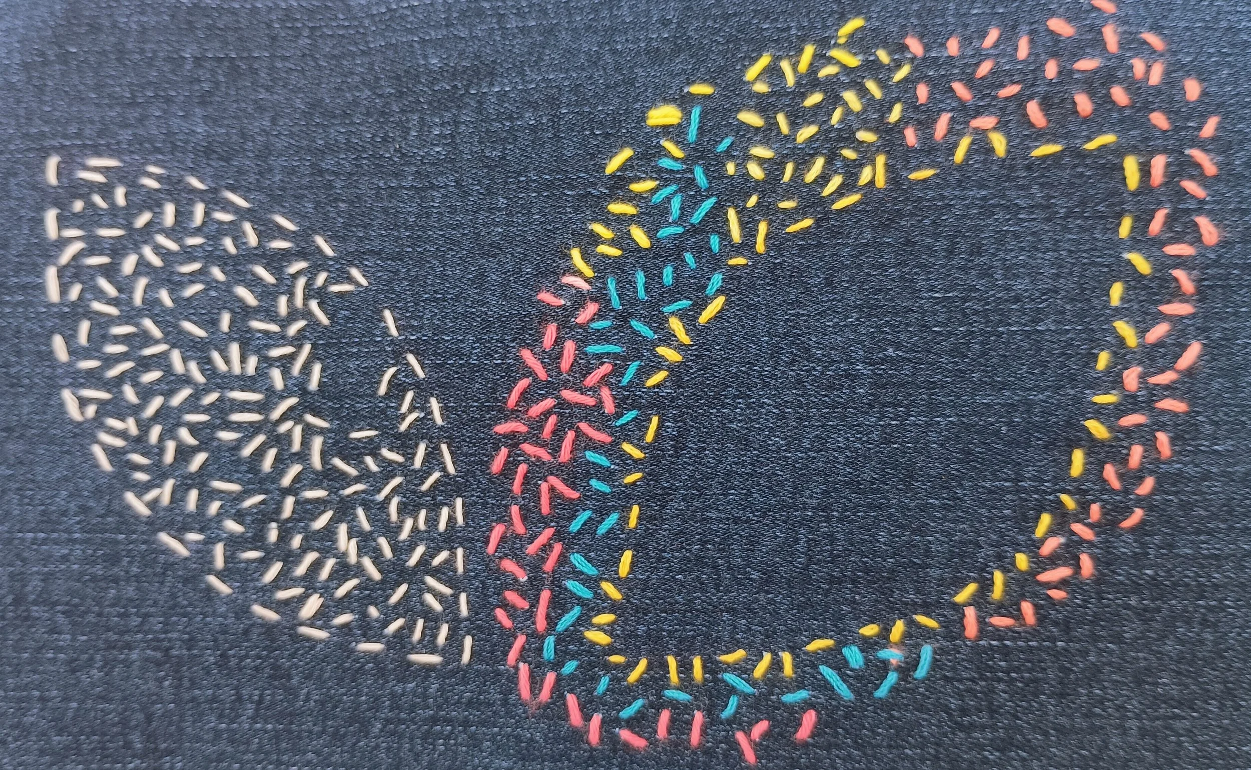 Colorful rice grains arranged on a black textured surface to create the word "LOVE."