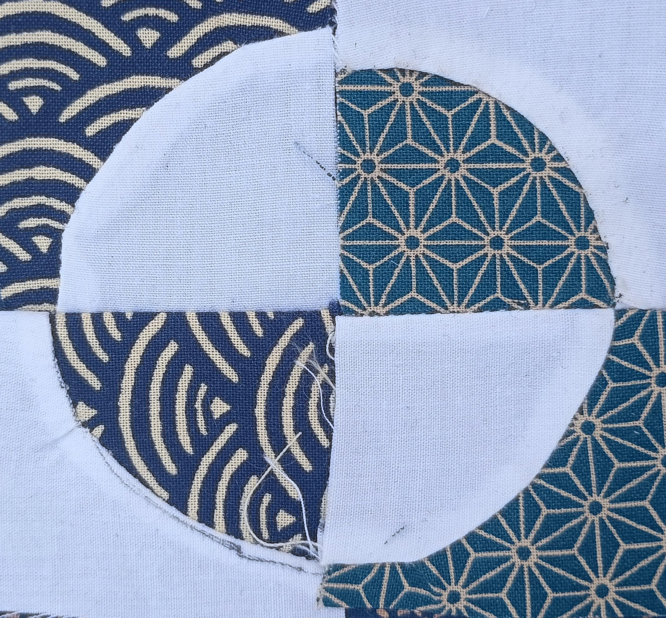 Close-up of torn paper with blue and beige geometric and wave patterns on a white fabric background.