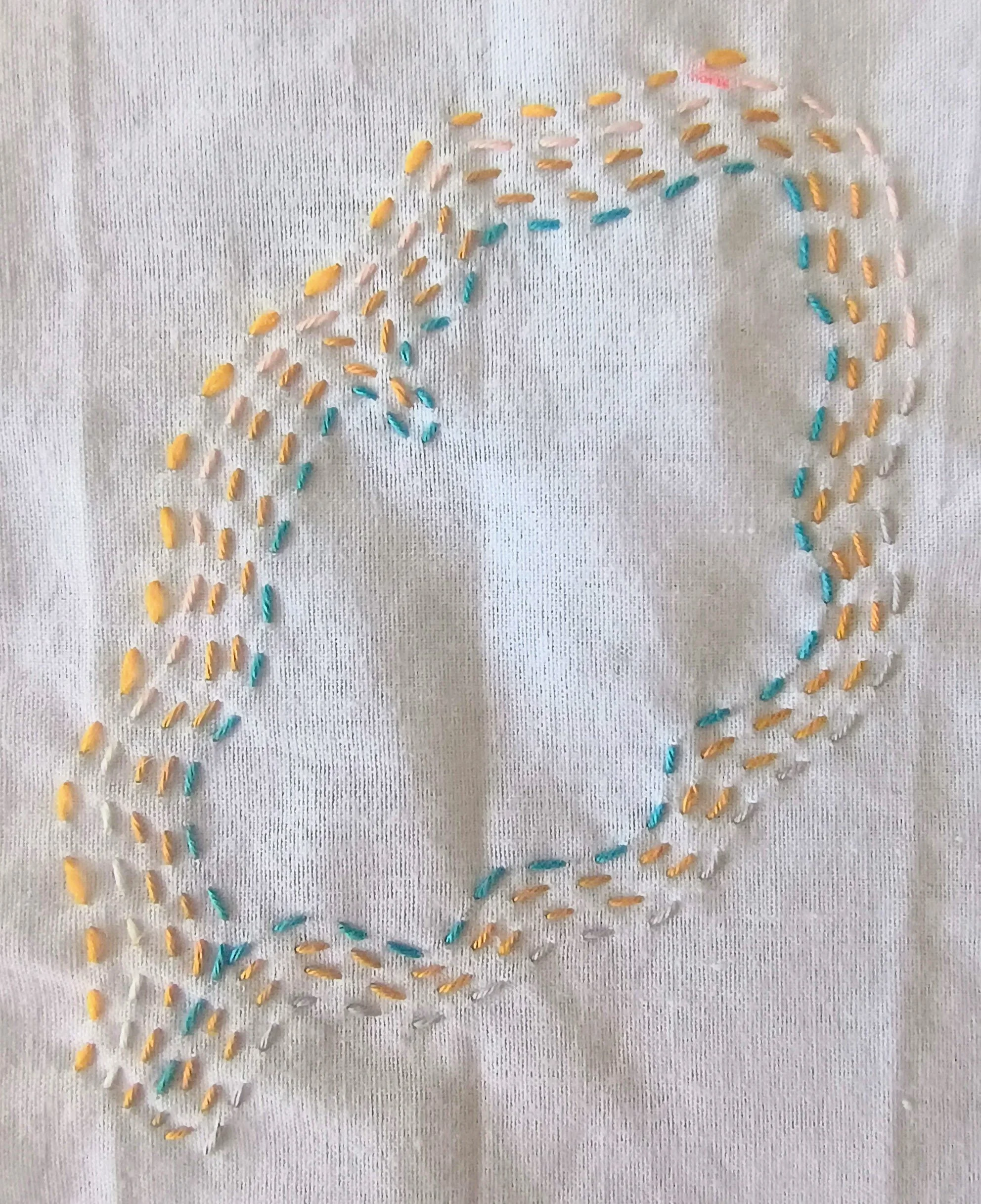 Colorful thread loops arranged in a pattern on a white fabric background.