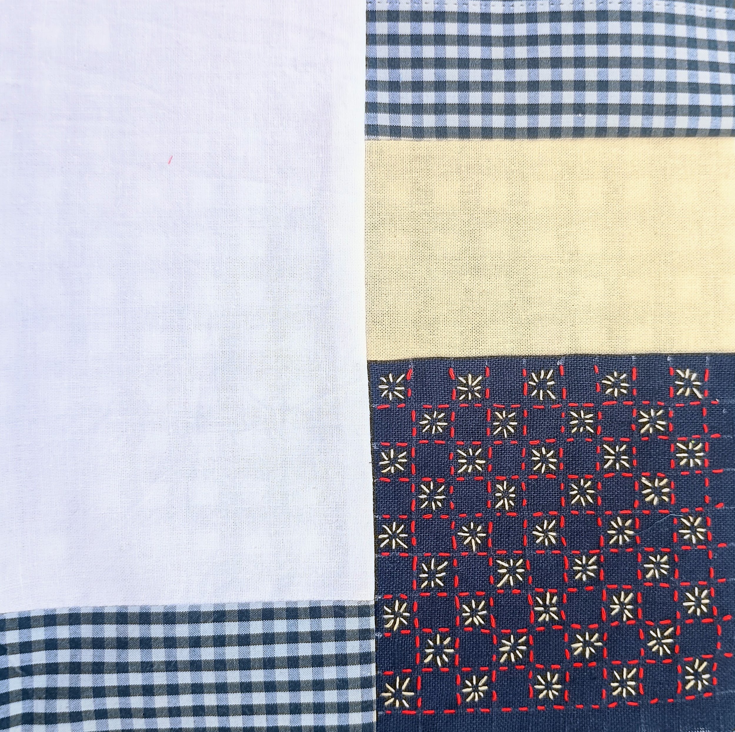 Close-up view of four different fabric swatches with various patterns and colors, including solid white, gingham check, yellow polka dots, and embroidered floral designs in navy blue with red accents.