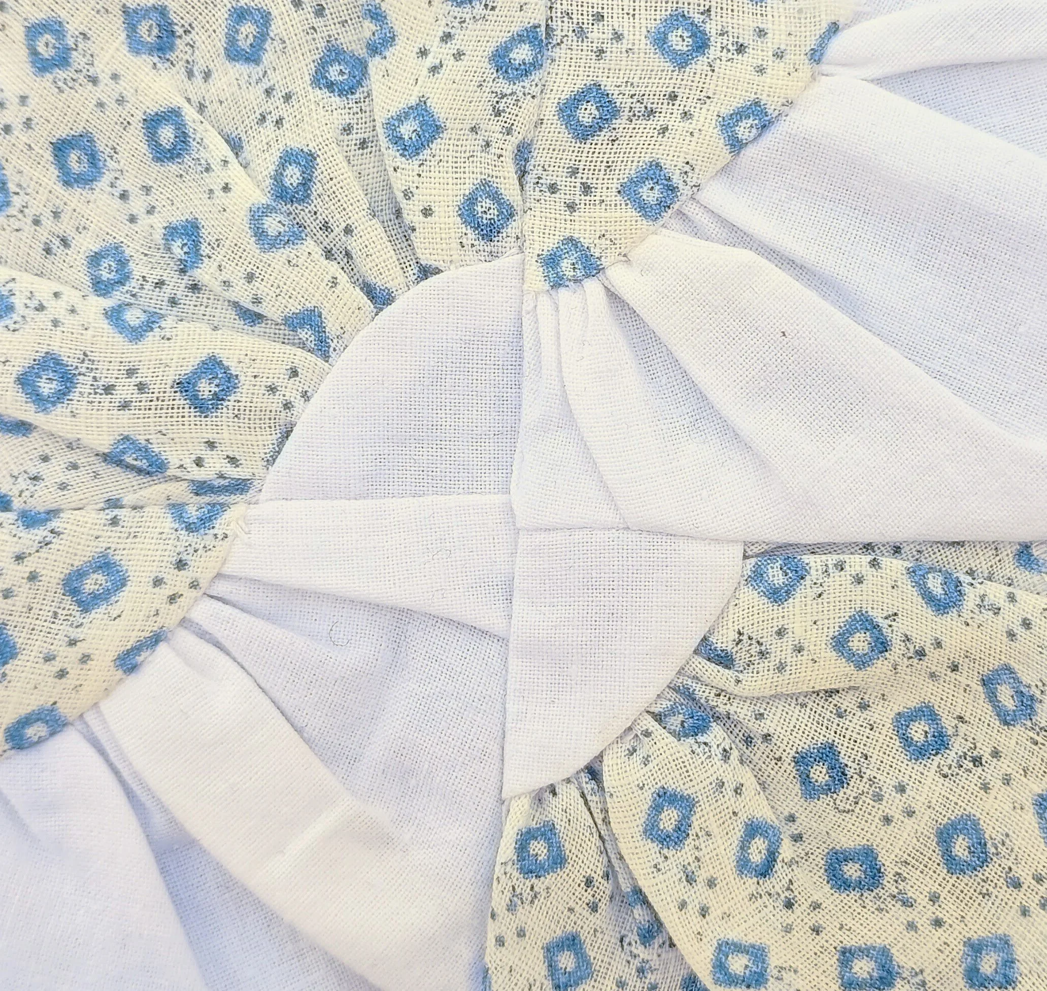 Close-up of white fabric with a blue floral or geometric pattern.