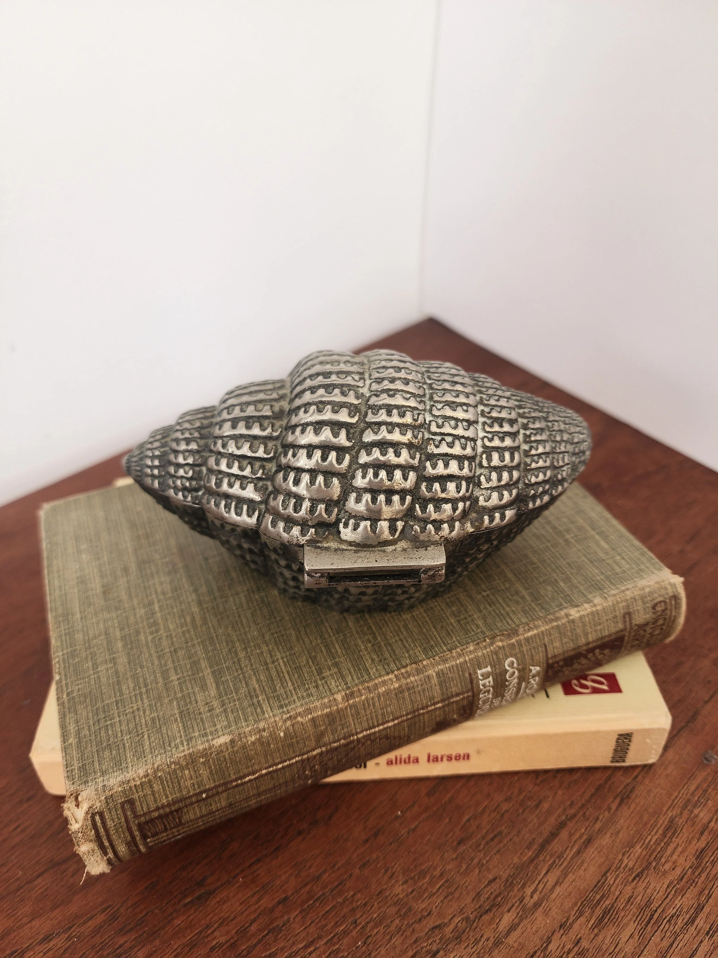 “Vintage seashell jewelry box with ribbed metal texture and blue velvet lining.”