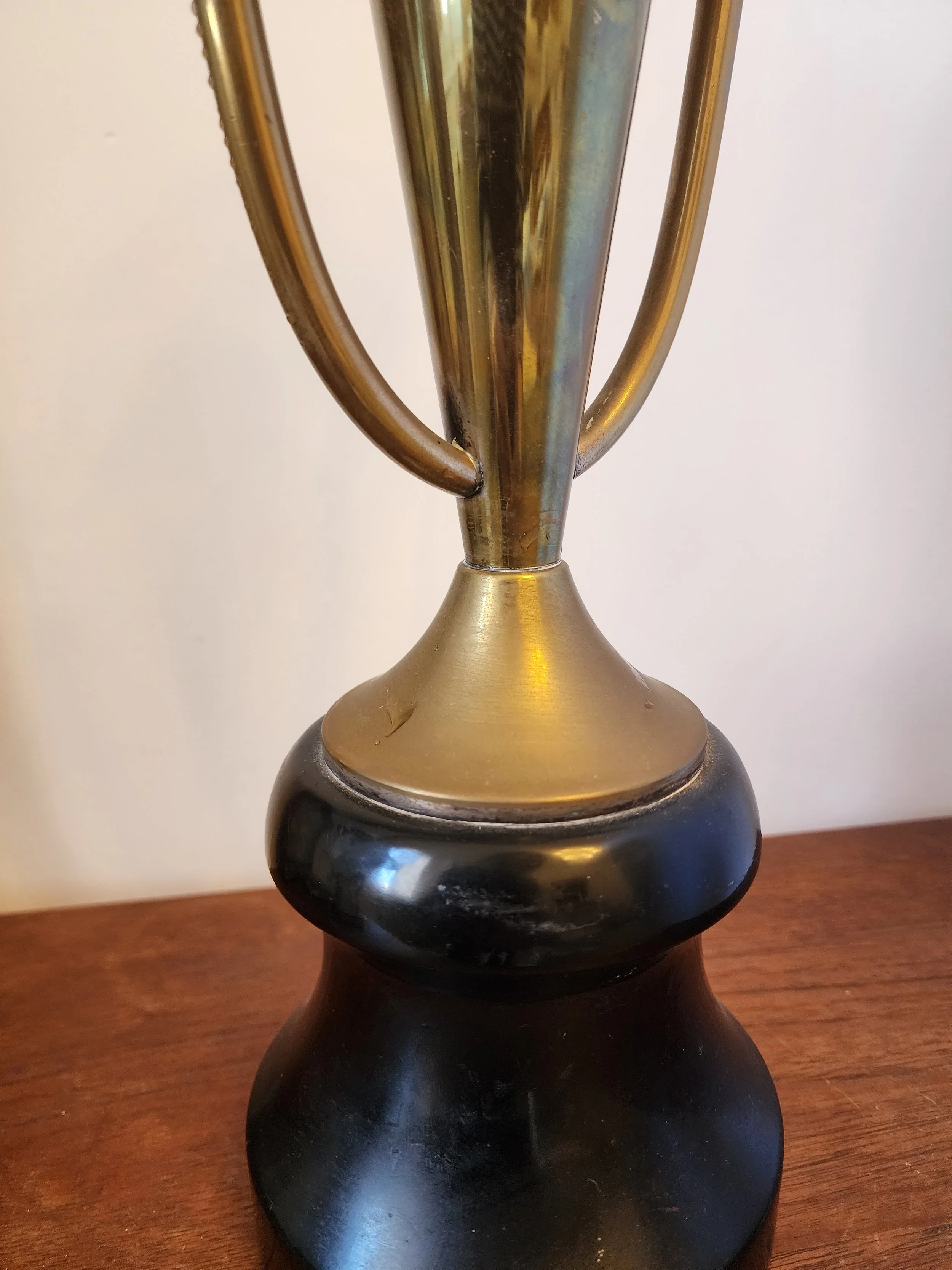side angle of tall vintage brass trophy with curved handles