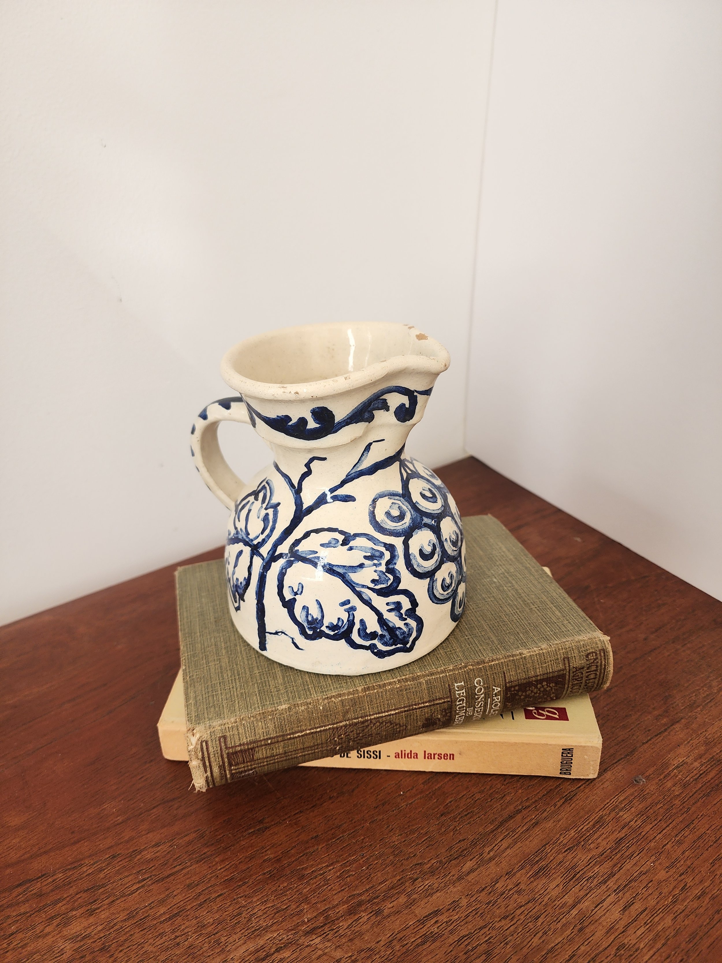 “Small Spanish folk art ceramic pitcher with blue leafy motif.”