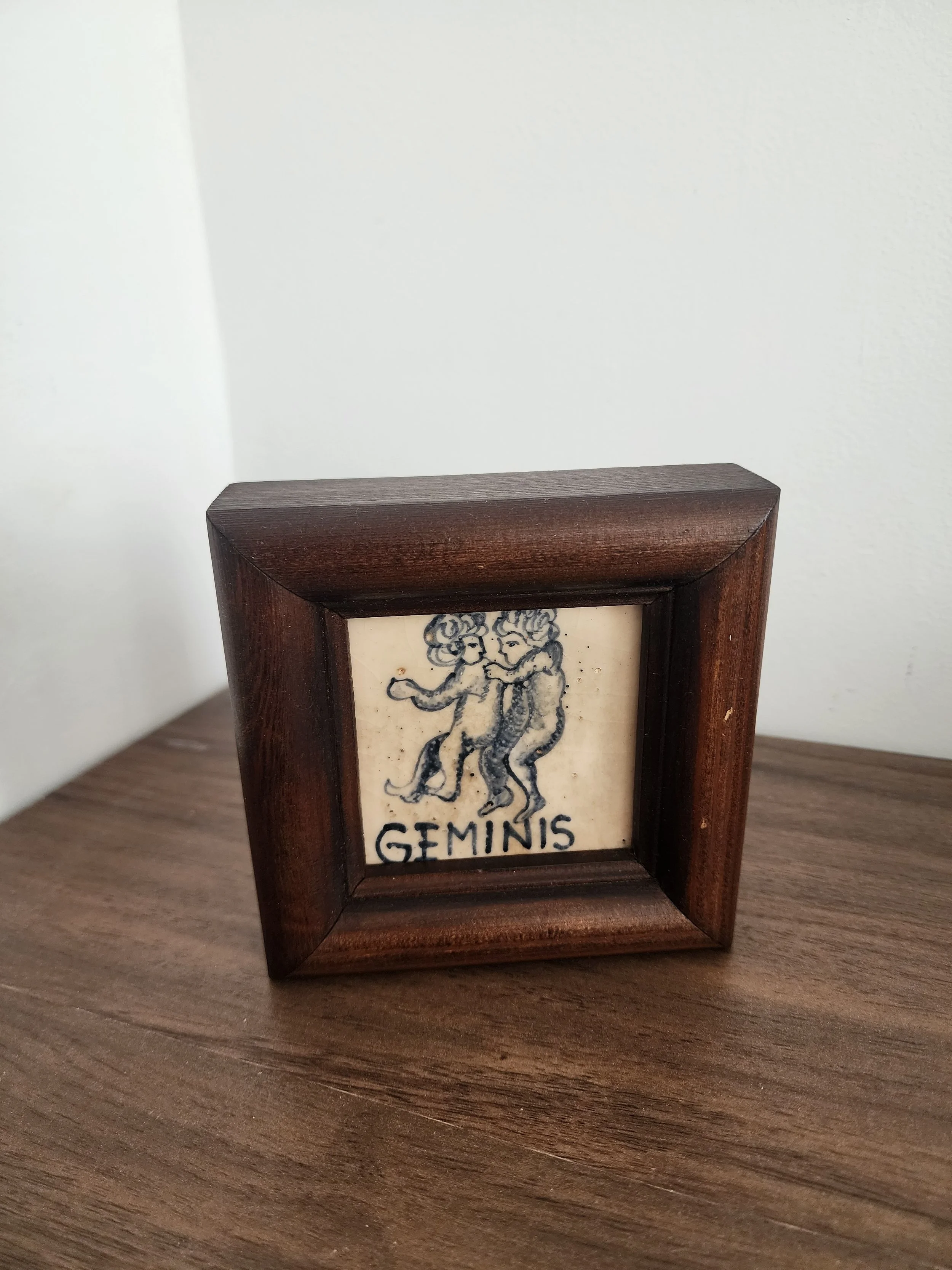 Hand-painted “Géminis” tile with blue figures on cream glaze.