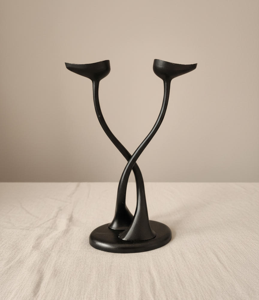 Mid-century modern black sculptural double candle holder on linen background.