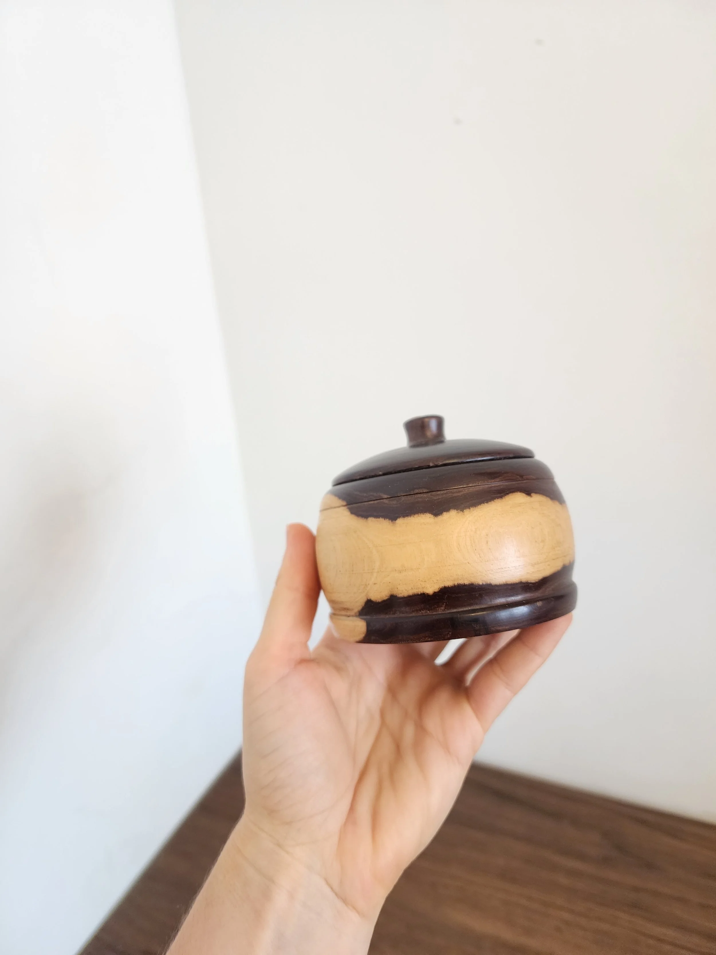 Close-up of wooden jar body showing smooth grain and glazed black lid with drip detail