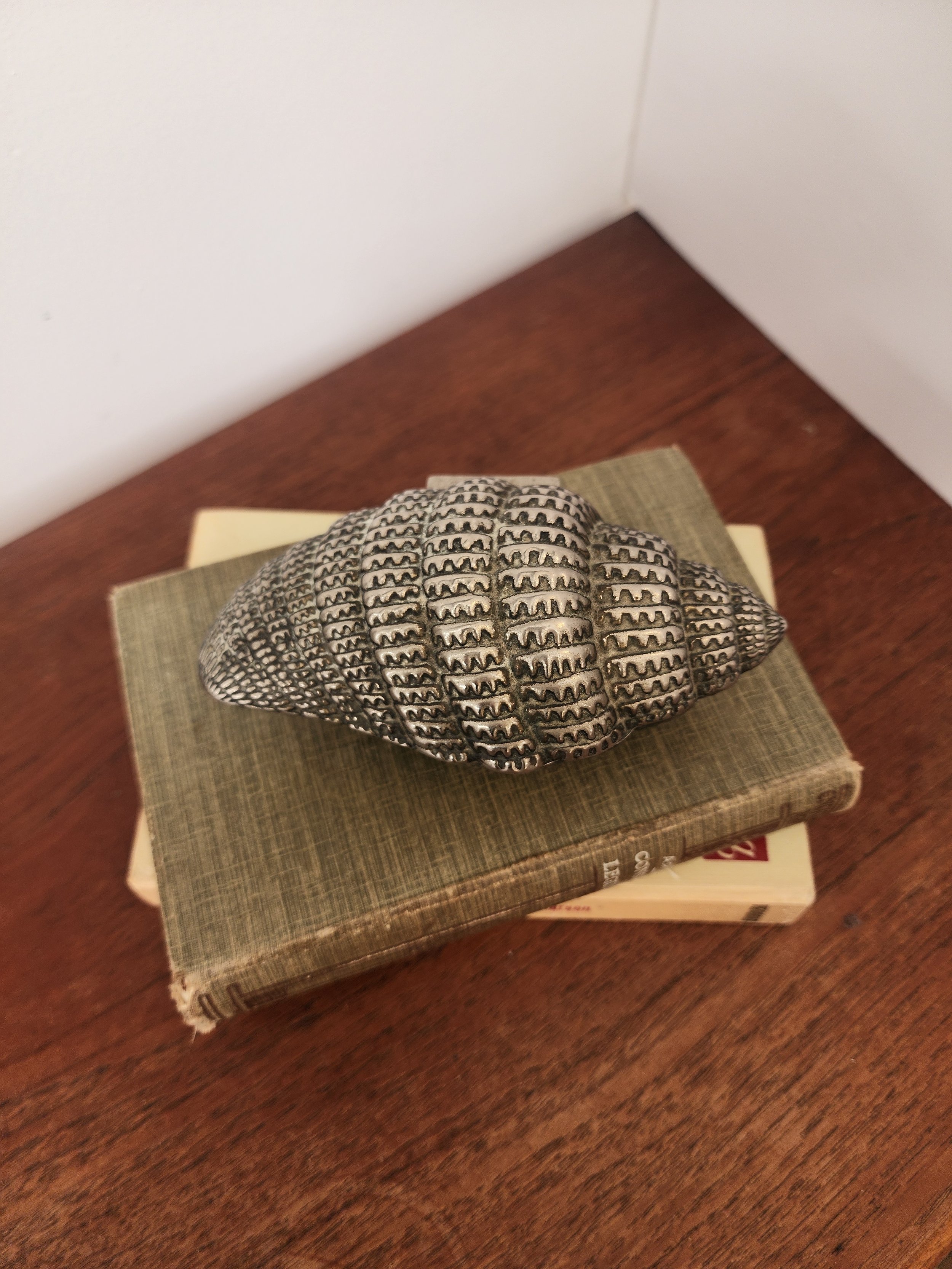 “Coastal-style metal trinket box shaped like a seashell with velvet-lined bottom compartment.”