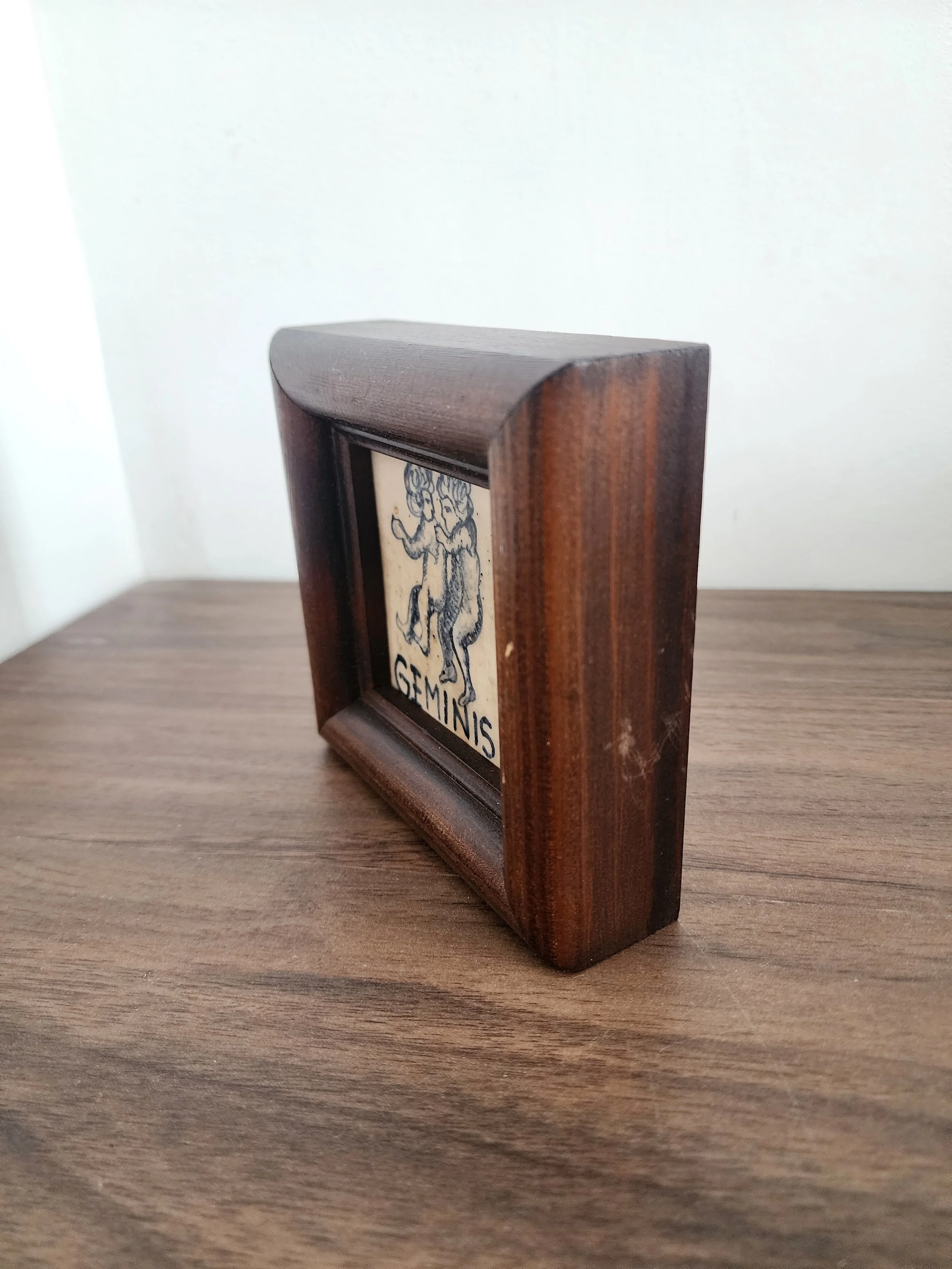 Vintage ceramic artwork of Gemini twins with dark wood frame.