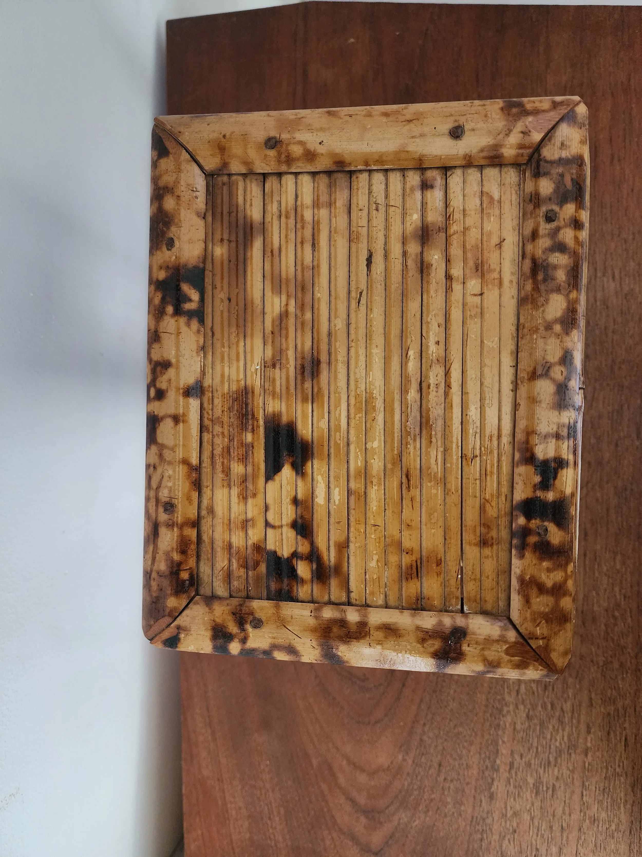 Low burnt bamboo plant stand on neutral backdrop.