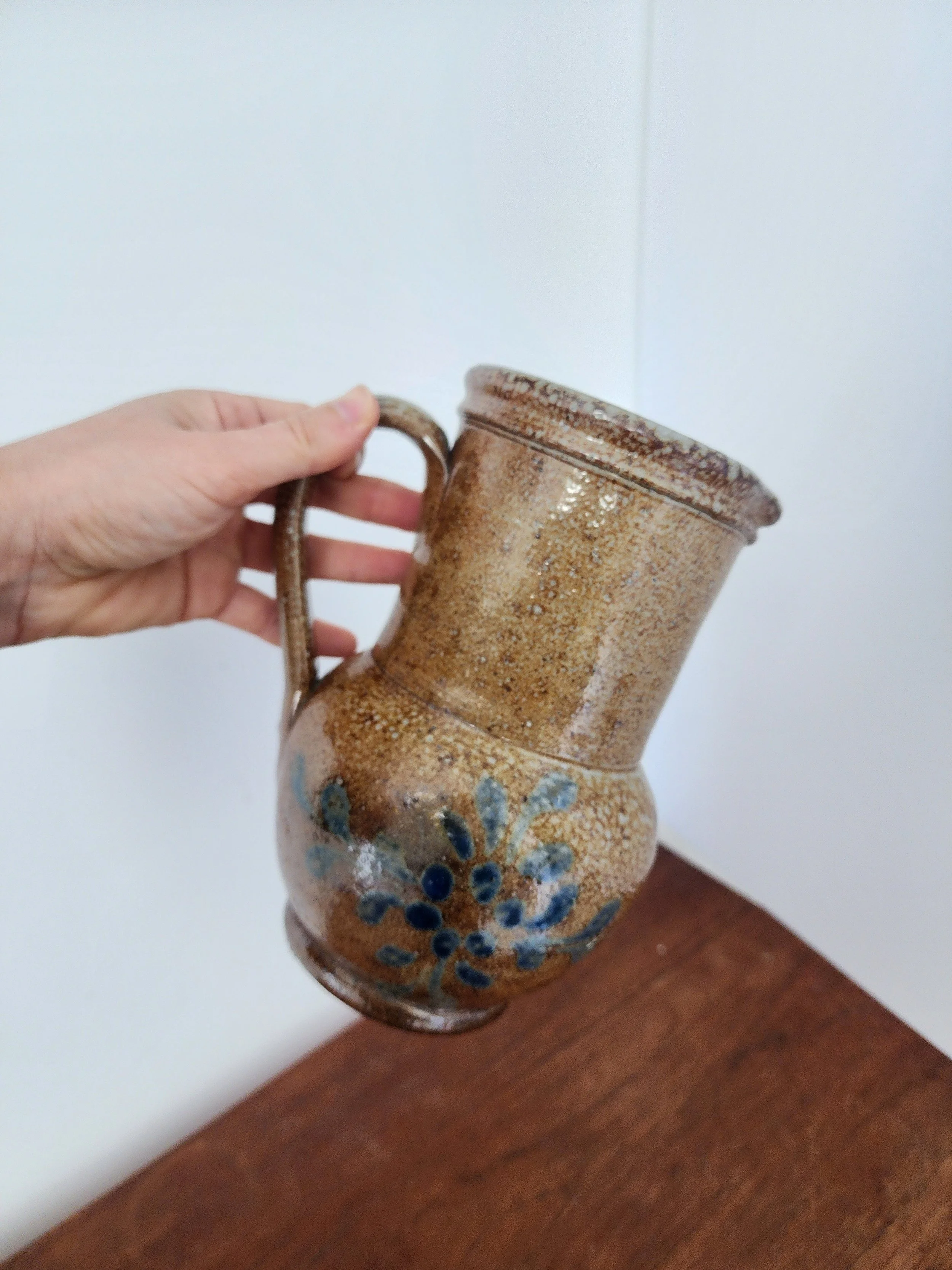 Vintage stoneware pitcher displayed upright for scale on neutral linen fabric.”