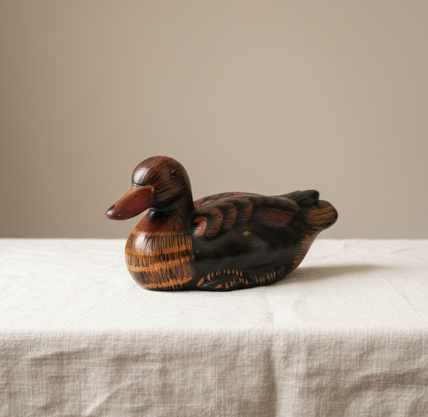 “Vintage ceramic duck figurine with hand-painted details displayed on a linen cloth.”