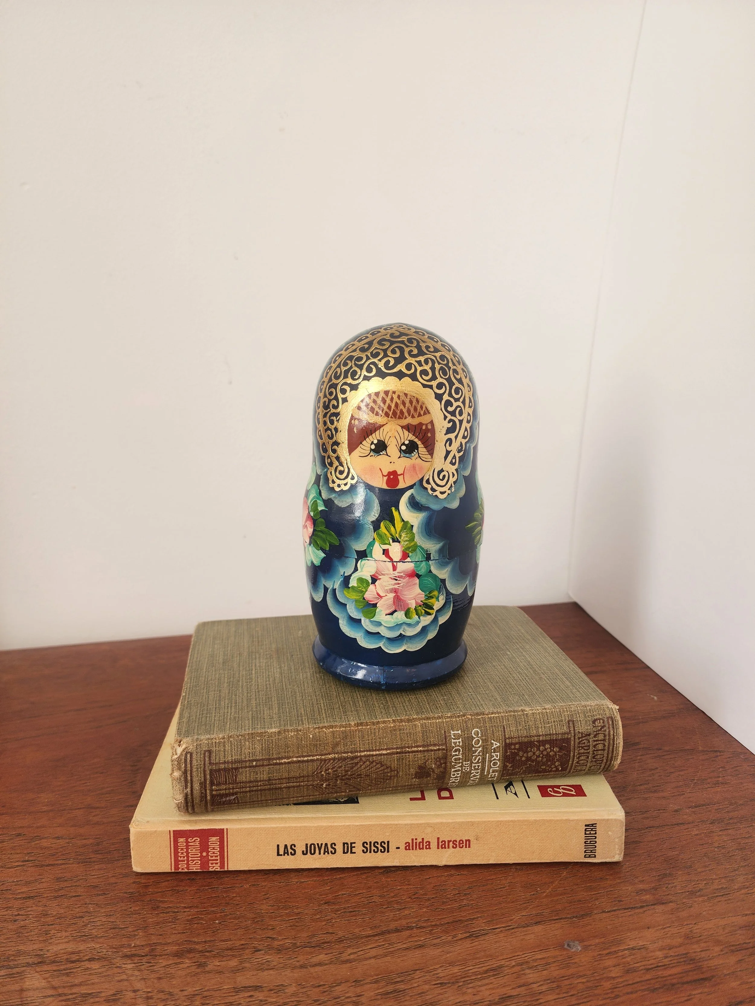 “Hand-painted nesting dolls in dark blue with folk art flowers arranged by size.”