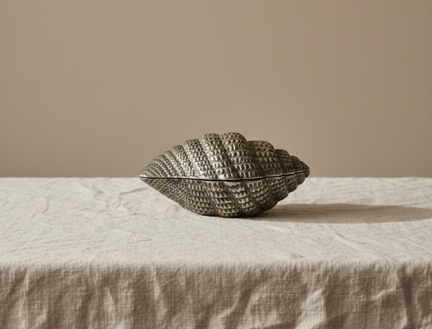 “Vintage metal seashell trinket box with blue velvet lining displayed on linen.”