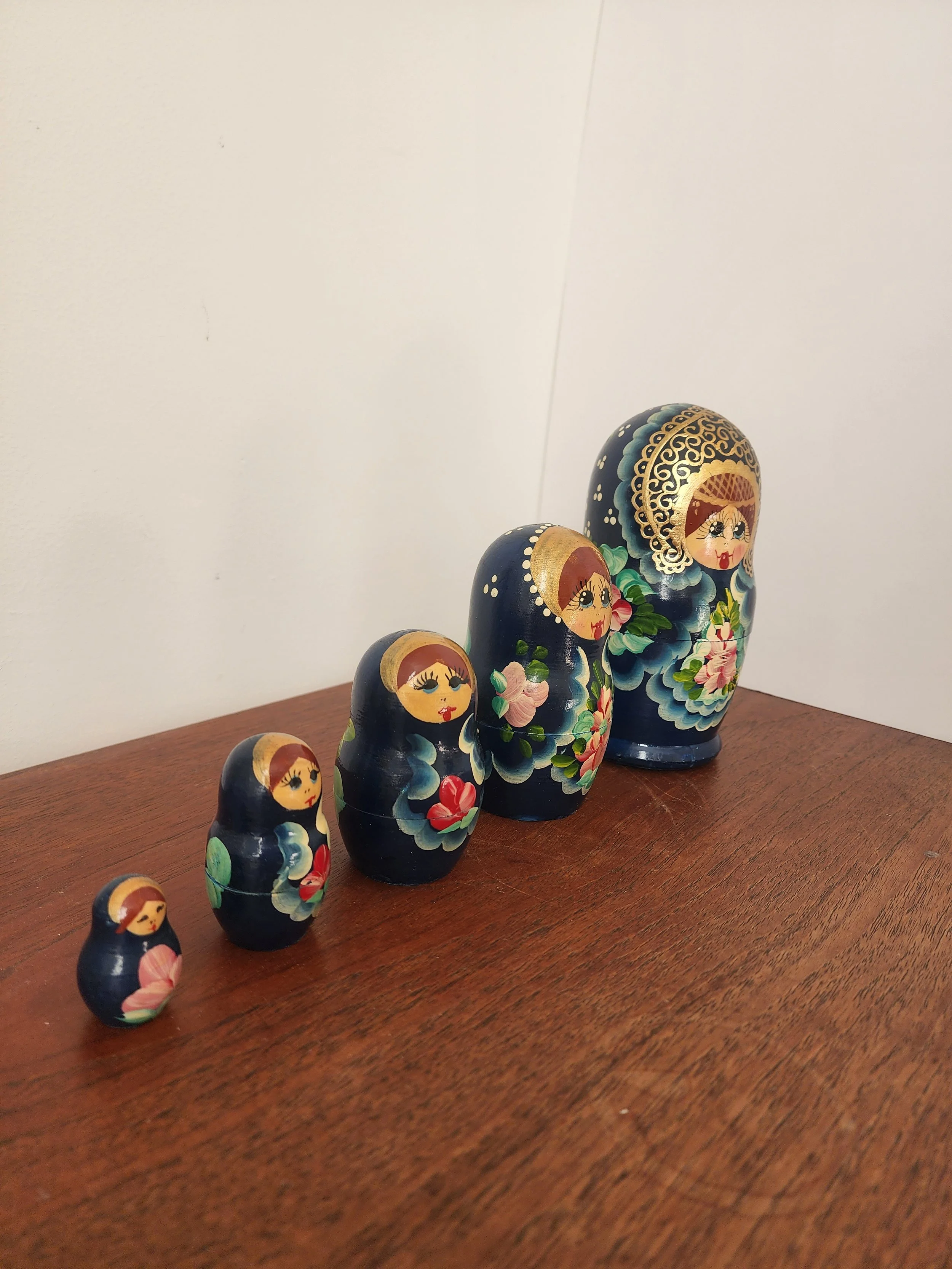 “Vintage blue nesting dolls with floral detailing photographed on a neutral background.”